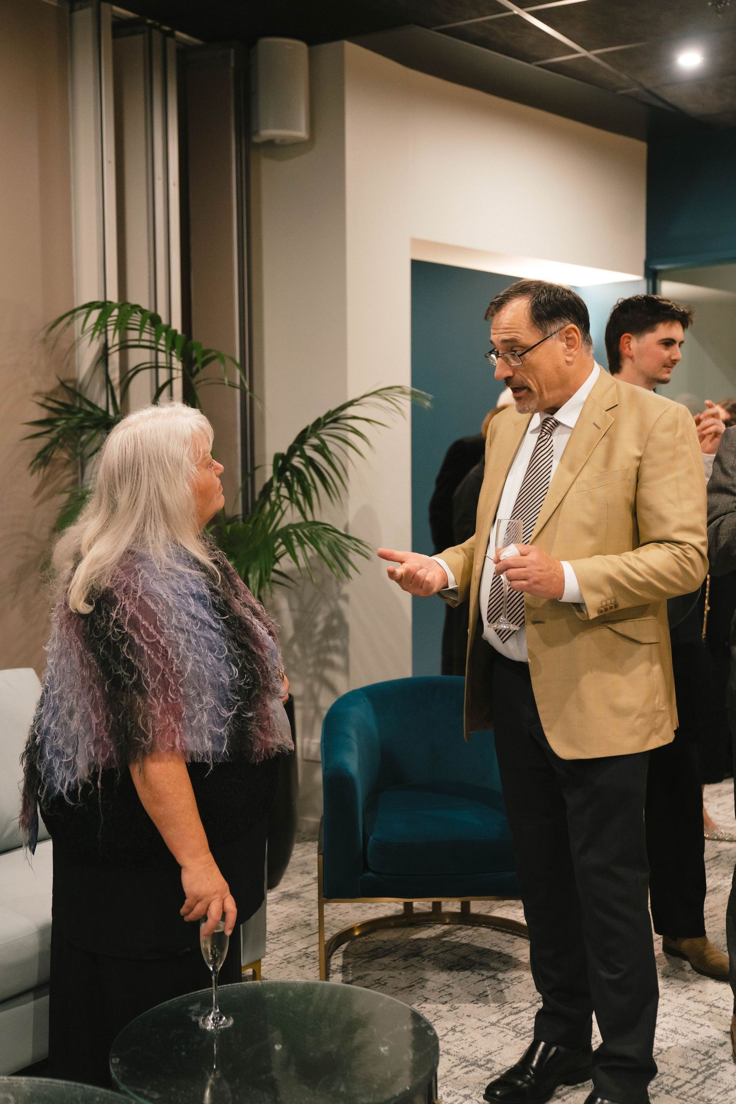 People having animated conversations at an indoor social gathering with modern decor.