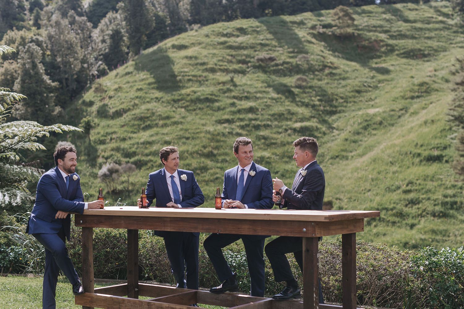 Officials meet at an outdoor wooden table in a scenic mountain landscape setting with lush green slopes in the background.