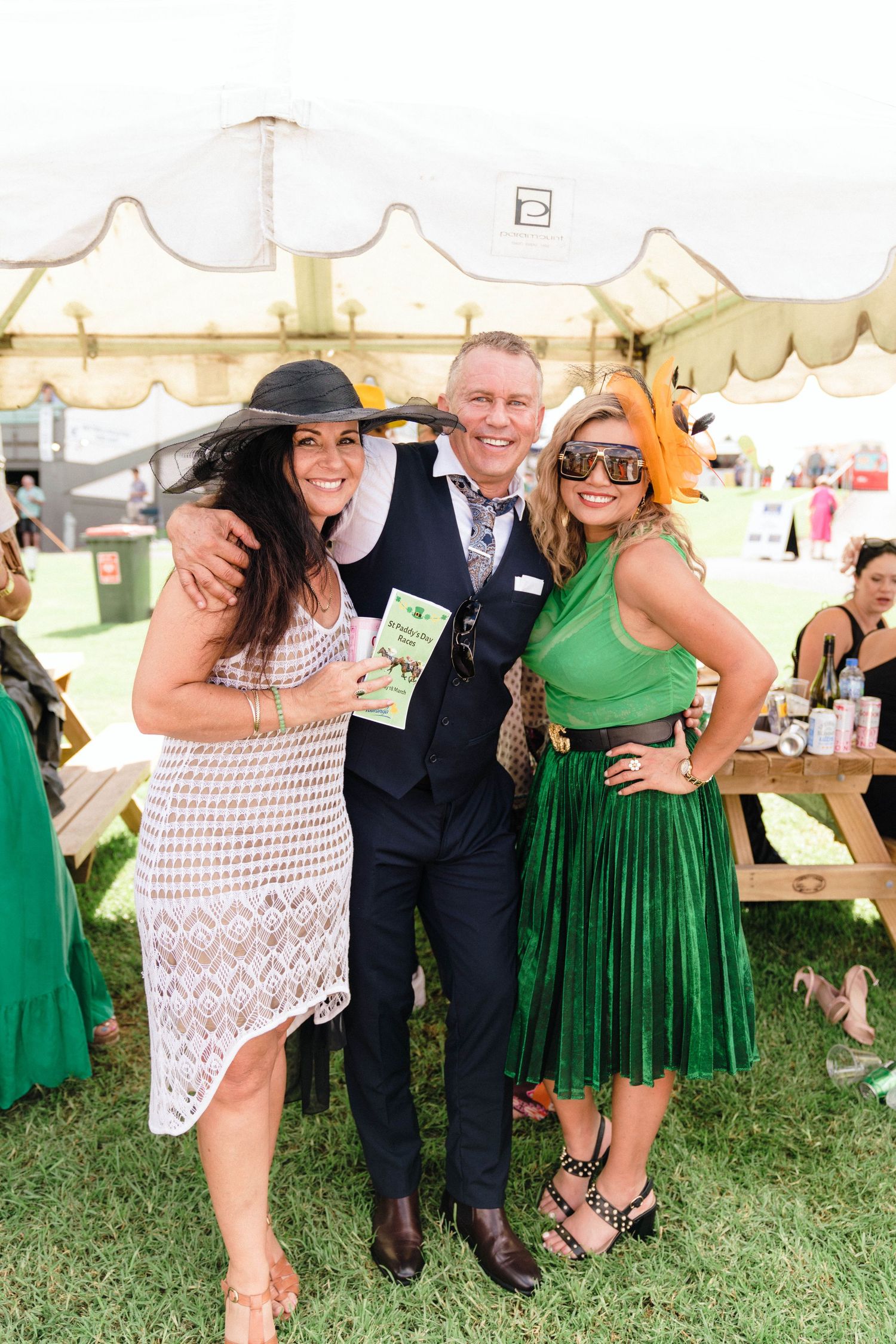 Friends posing together at an outdoor event wearing summer attire.