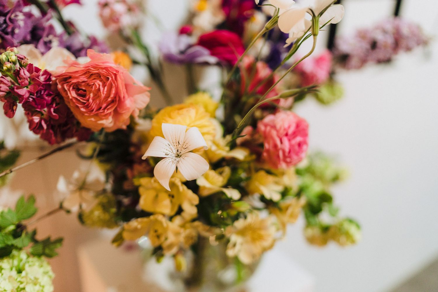 A vibrant floral arrangement with roses and mixed blooms in pink, yellow and coral tones.