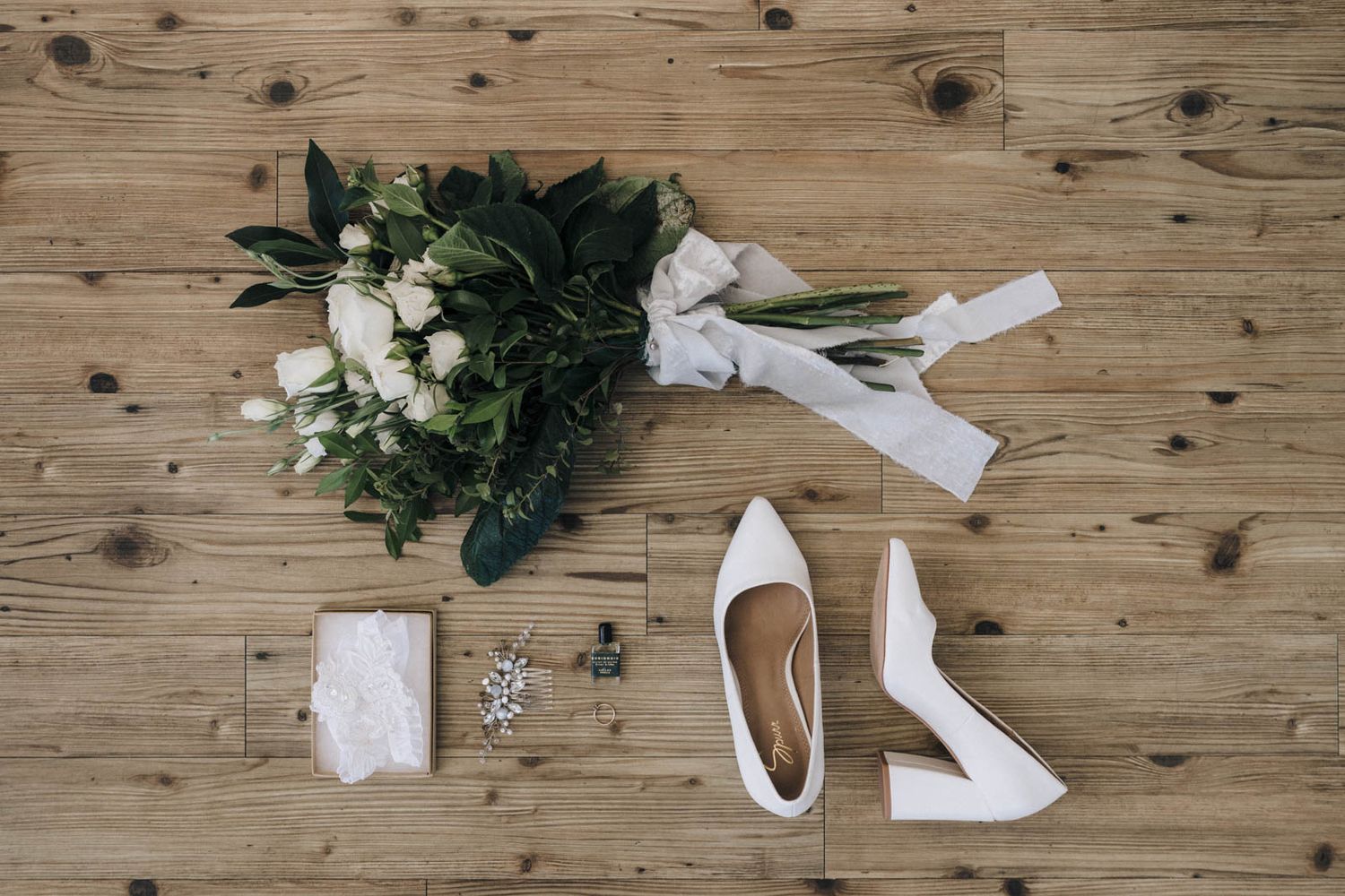 Four connected images showing a rustic wood background with scattered white ribbons and dark green foliage creating a flat lay design.