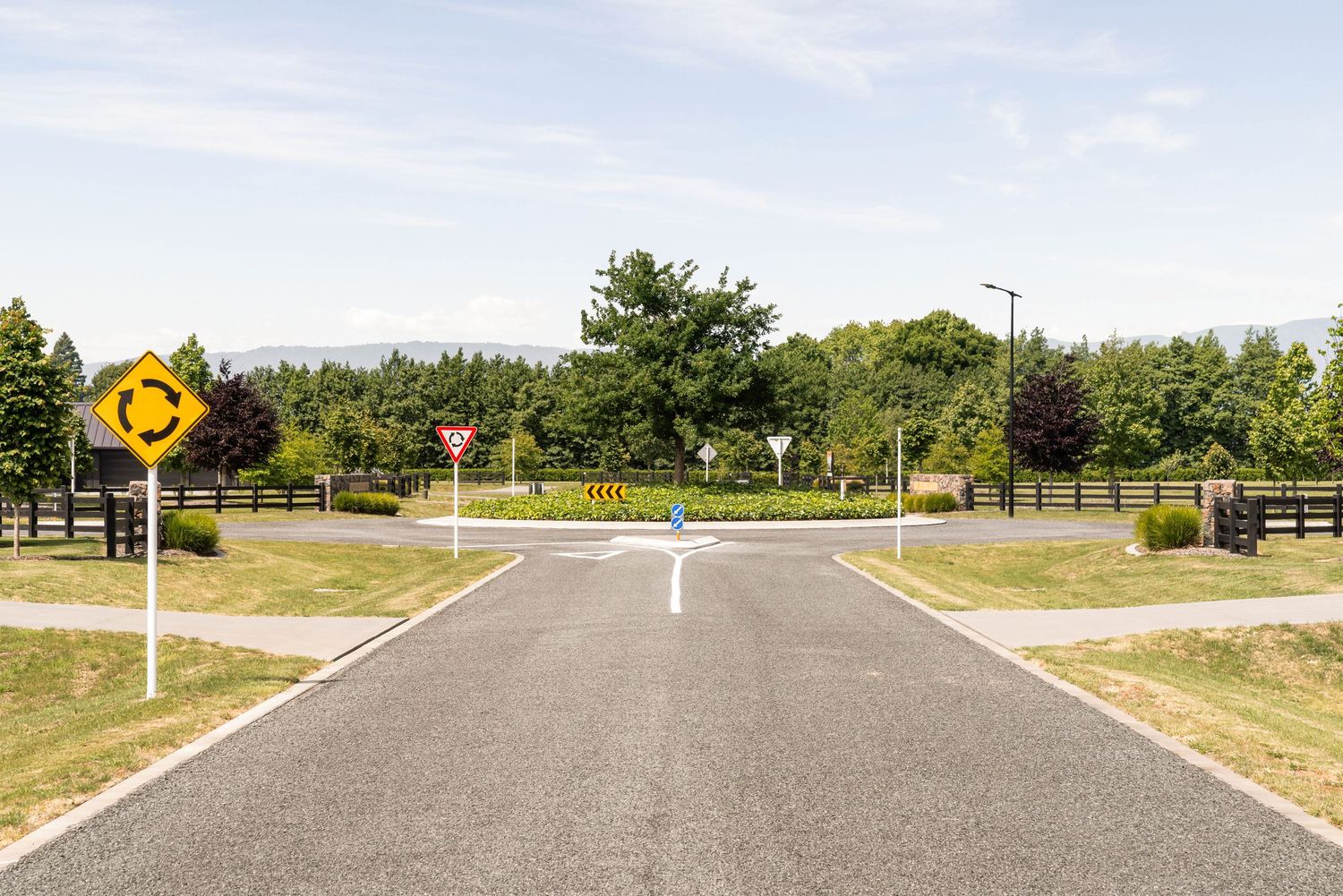 Rural intersection with traffic signs and white road markings.