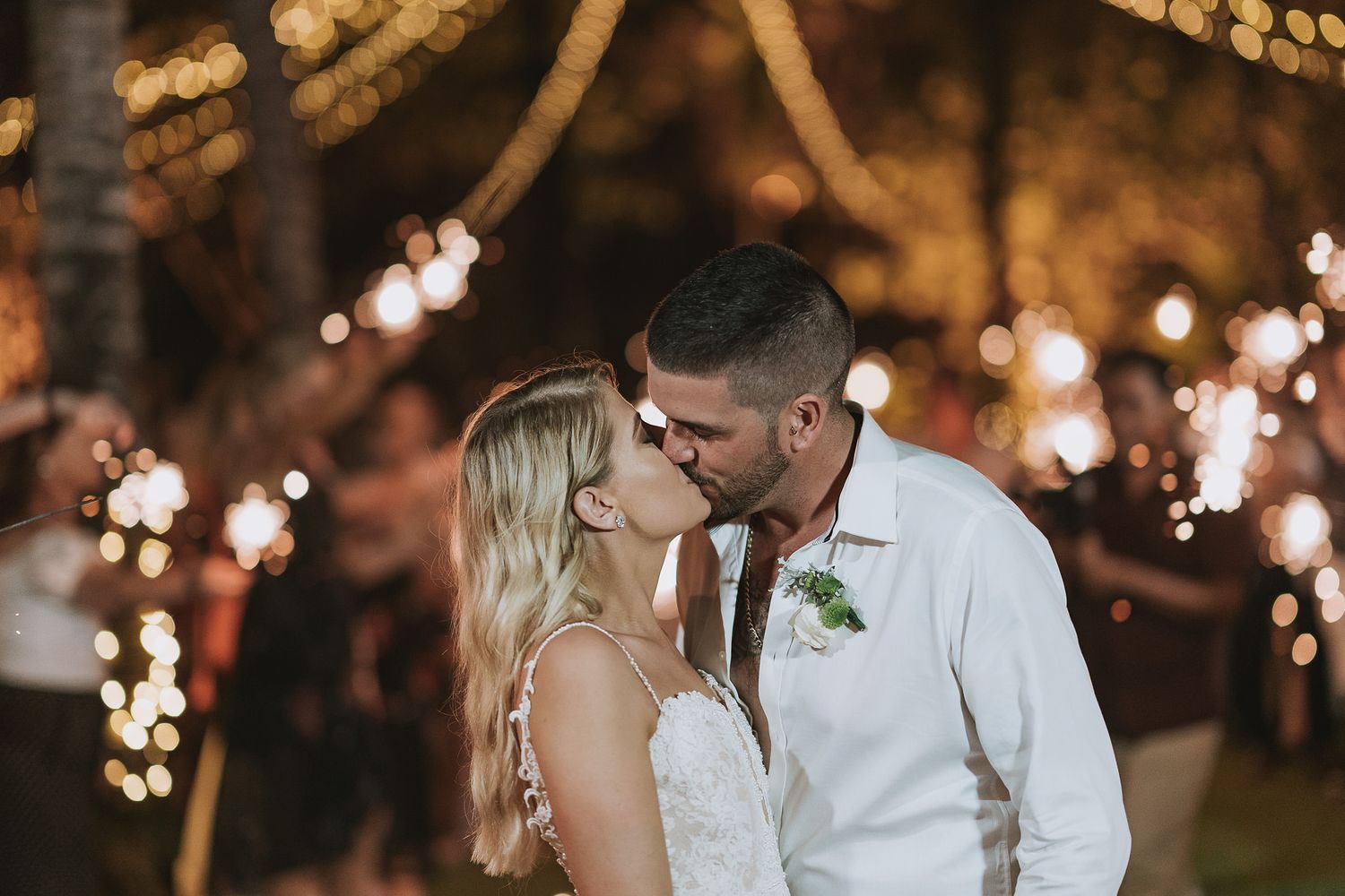 Romantic evening moment under string lights at outdoor wedding reception.