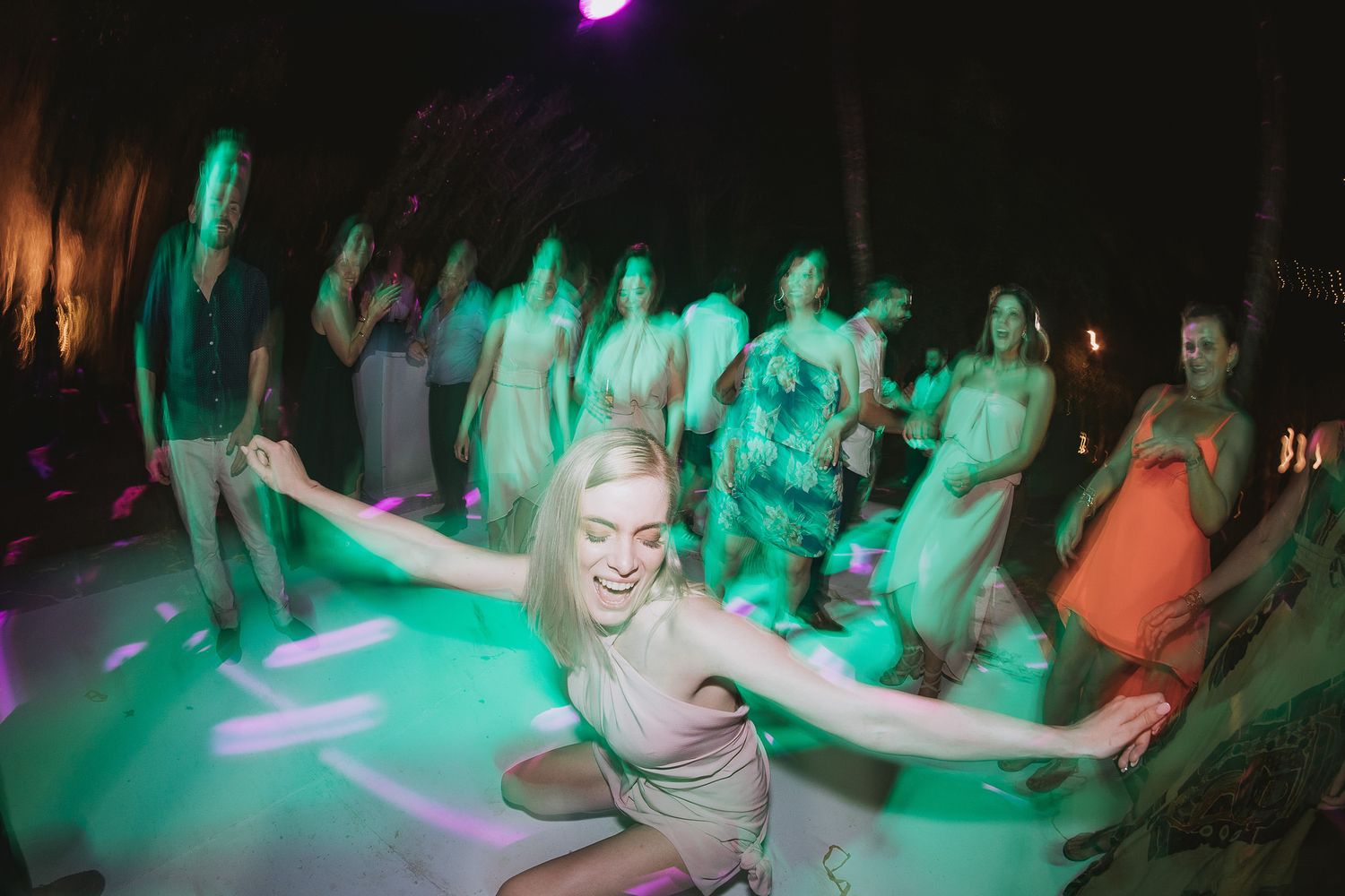 Dance floor illuminated with vibrant green lighting as guests celebrate at nighttime party.