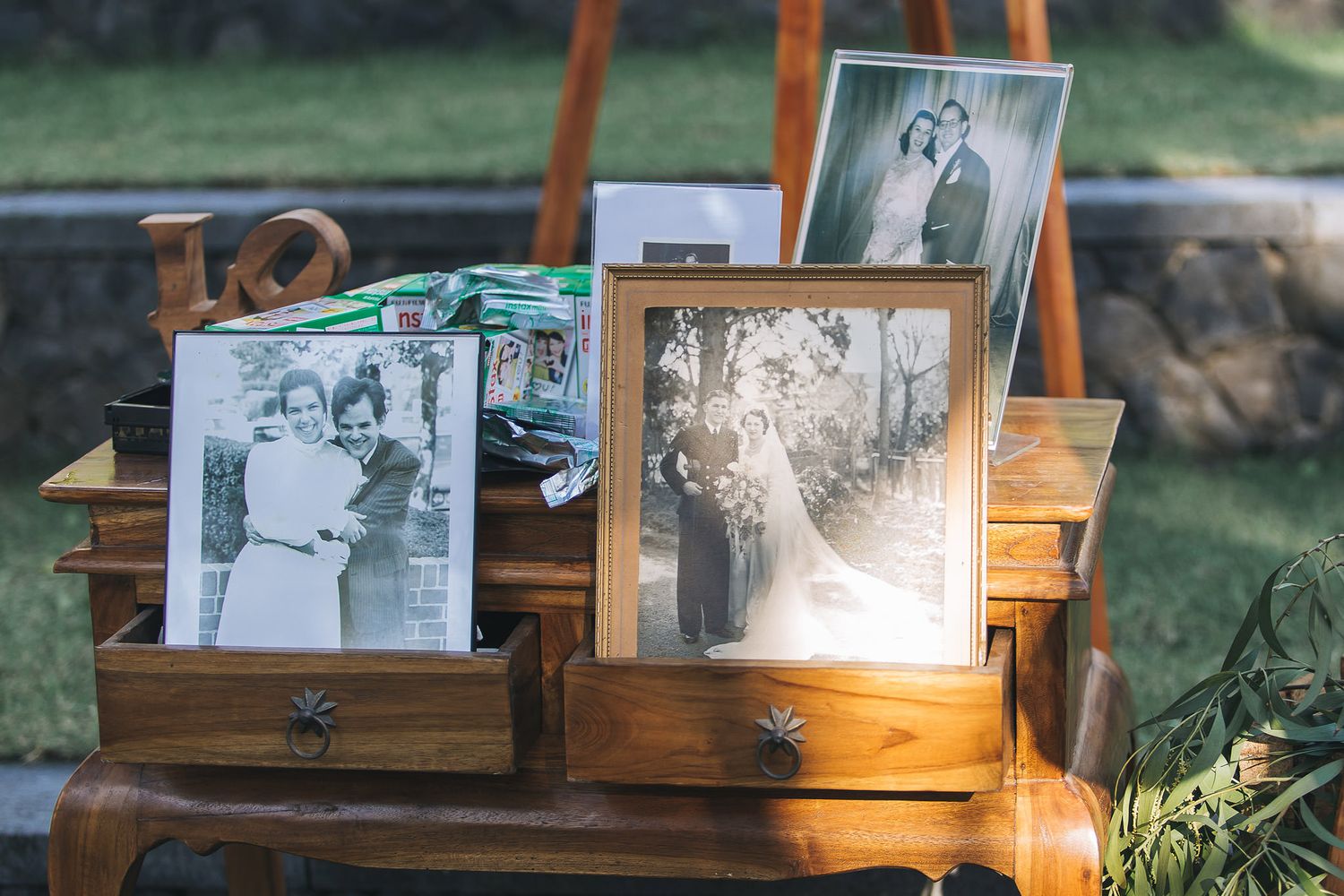 Rustic wooden display showcases vintage photographs in frames against natural outdoor setting.