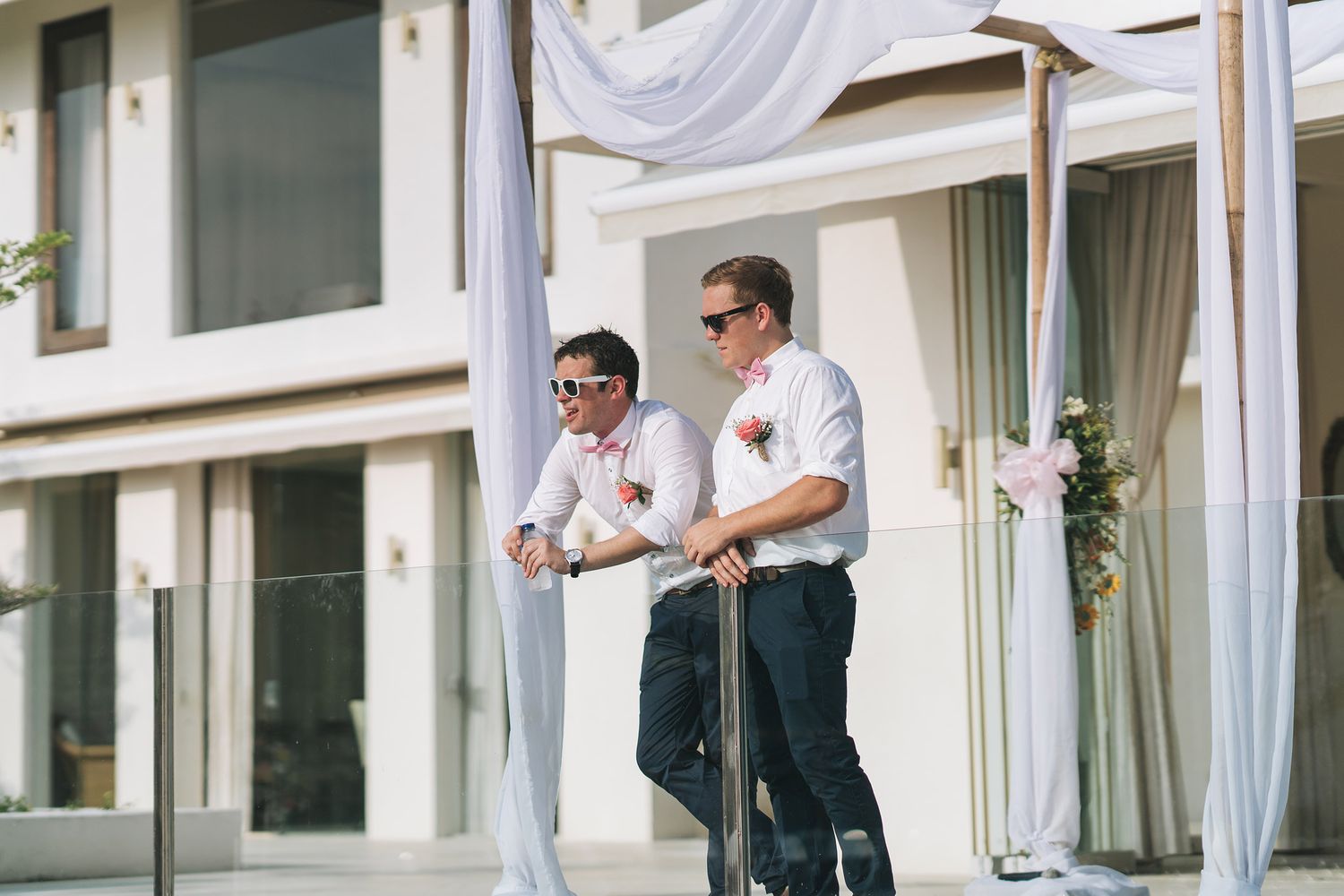 Two people in formal attire standing on a covered patio outside a building.
