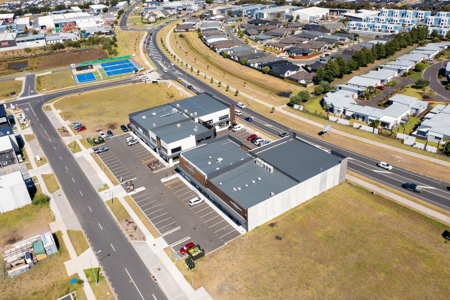 Aerial view of a modern commercial building complex with parking lots and surrounding residential area.