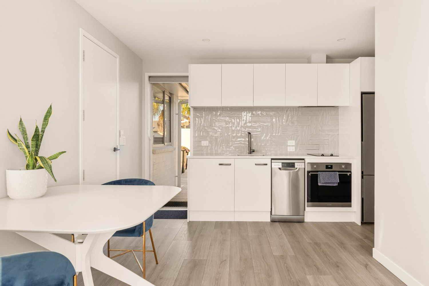 Sleek open concept kitchen with white cabinetry and modern appliances flows into living space.
