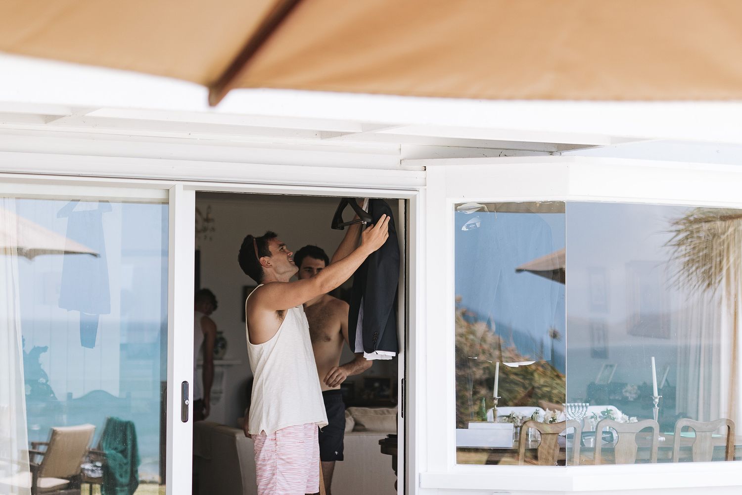 Person cleaning windows of a coastal building with ocean views and palm trees visible in the background.