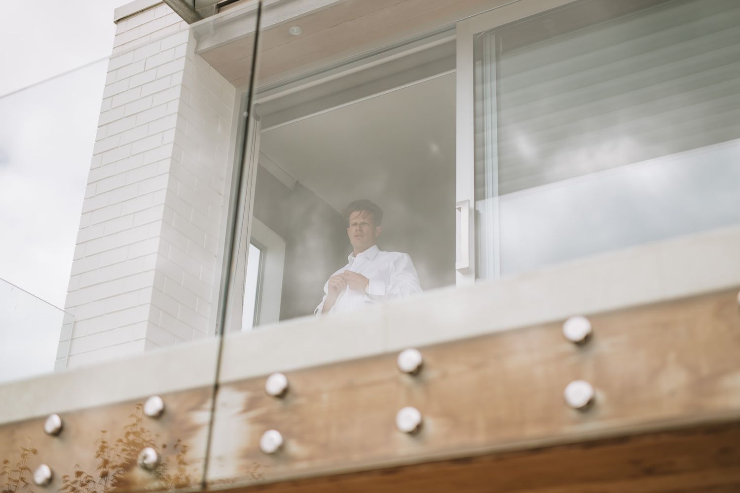 Someone looking down through a modern window with white walls and architectural wood beam details below.