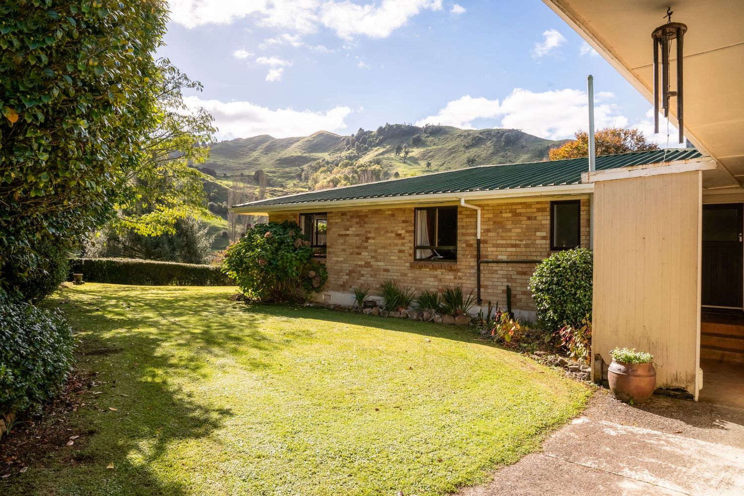 Stone and cream colored house with well-maintained lawn and mountain backdrop.