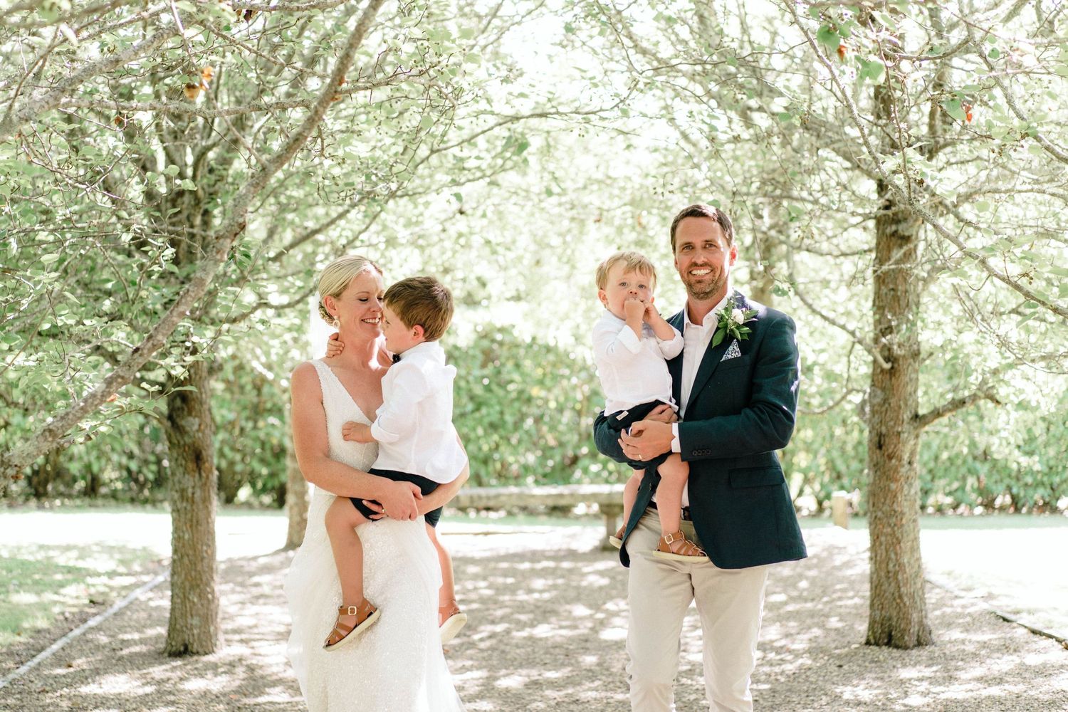 A couple dances in an outdoor garden setting under blooming trees at their wedding celebration.