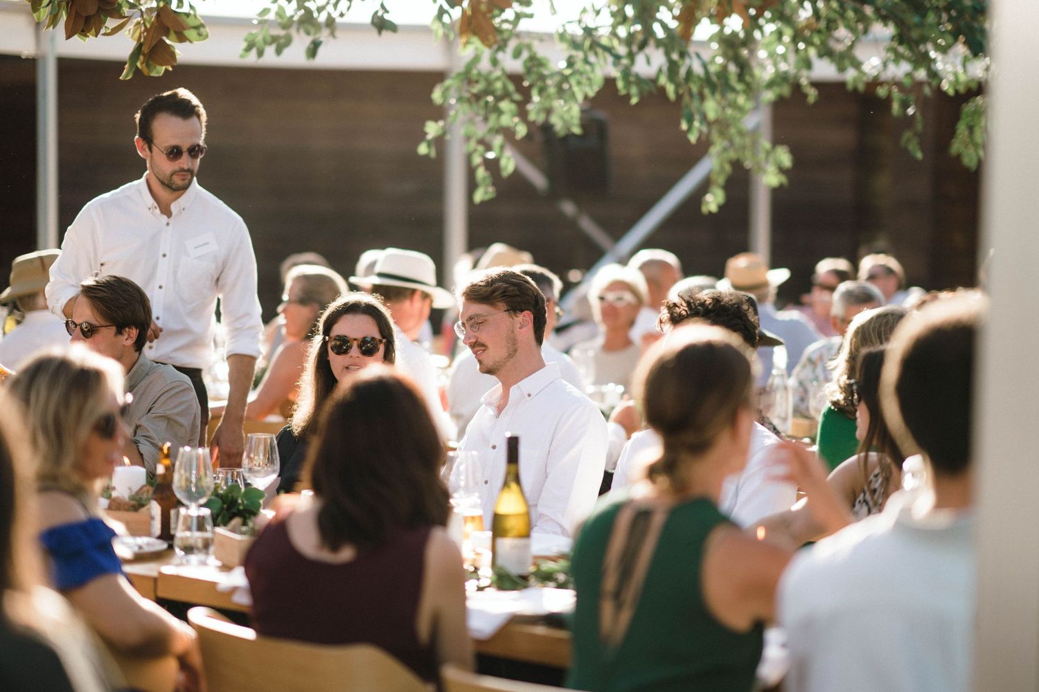 Wedding guests enjoying a festive outdoor dinner reception under string lights.