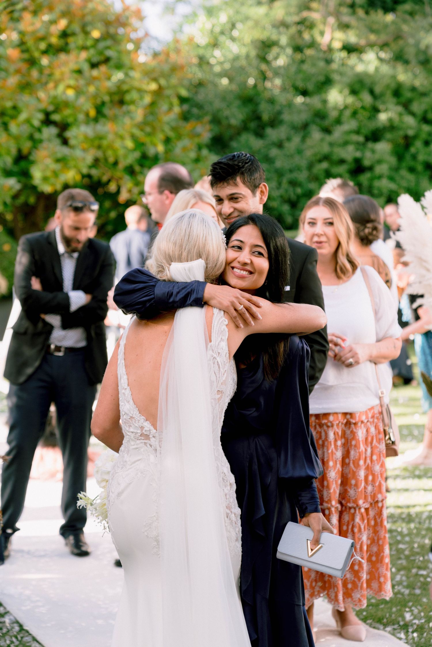 Wedding guests share warm embraces and congratulations during outdoor reception celebration.