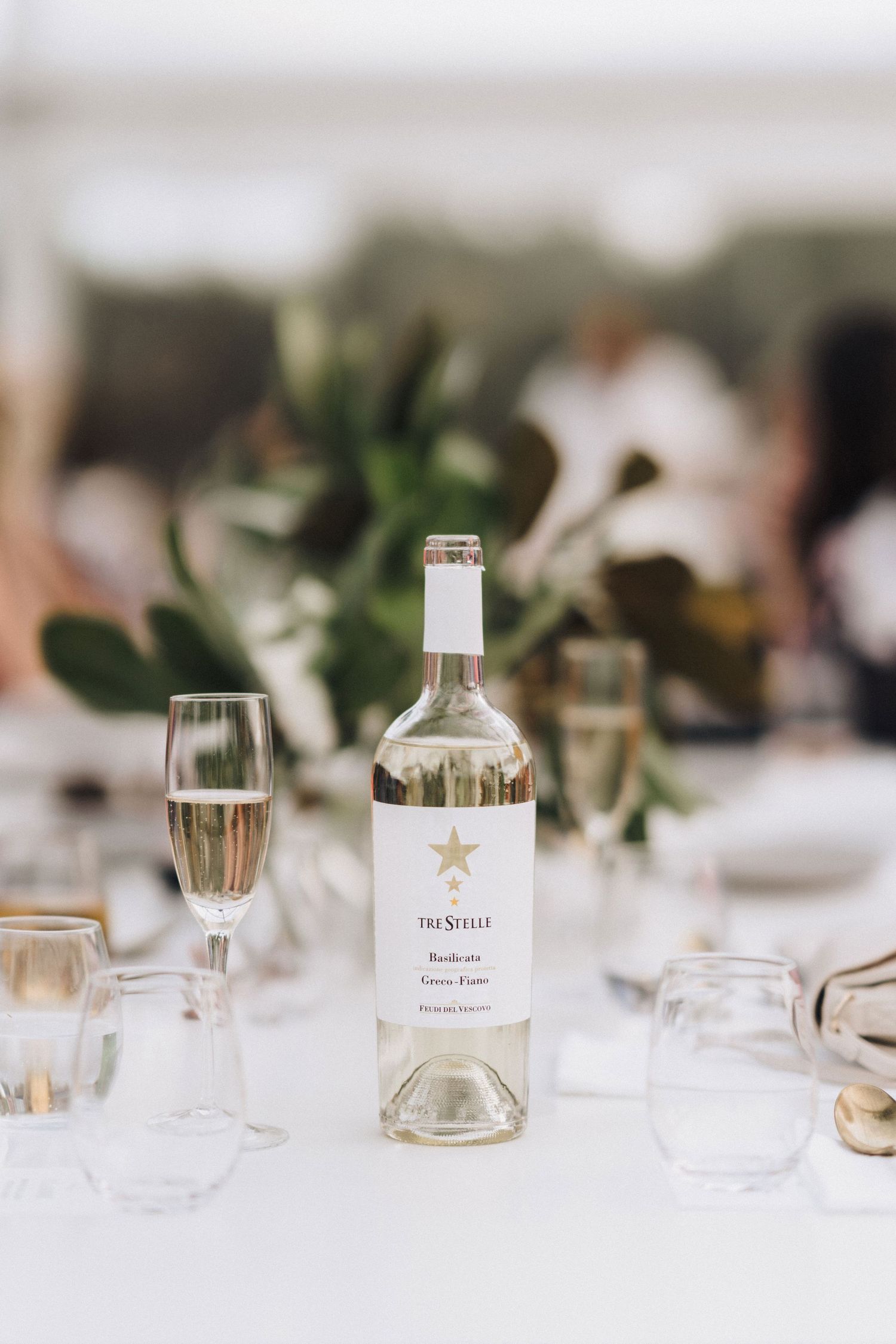 Elegant table settings with glass bottles and minimalist decor at wedding reception.