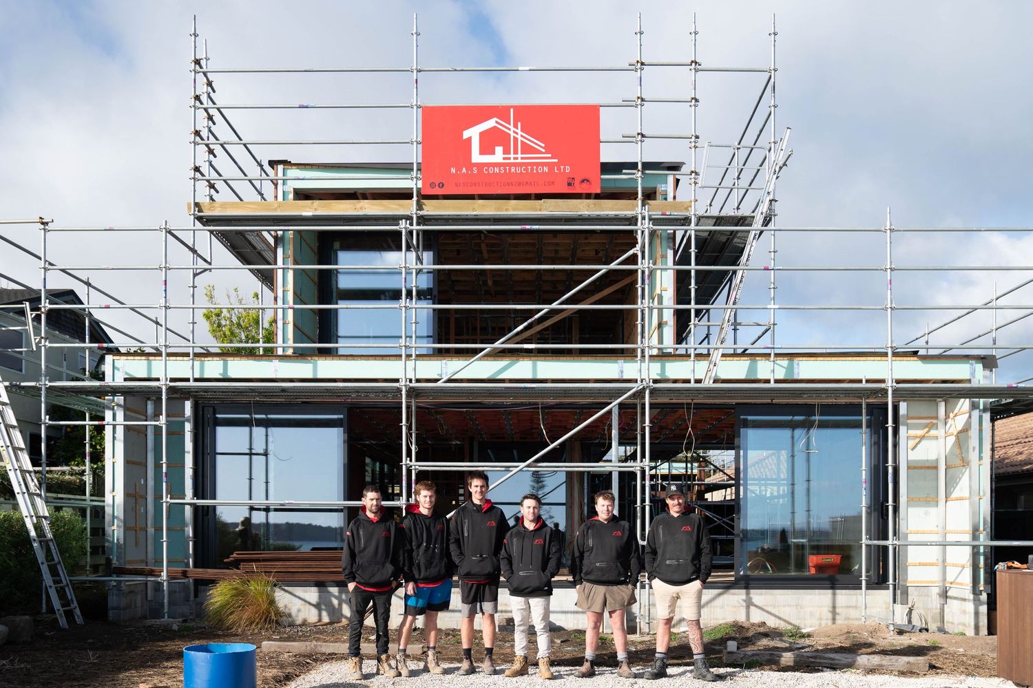 Construction progress photos showing stages of modern home build with scaffolding and glass installations from foundation to finish.