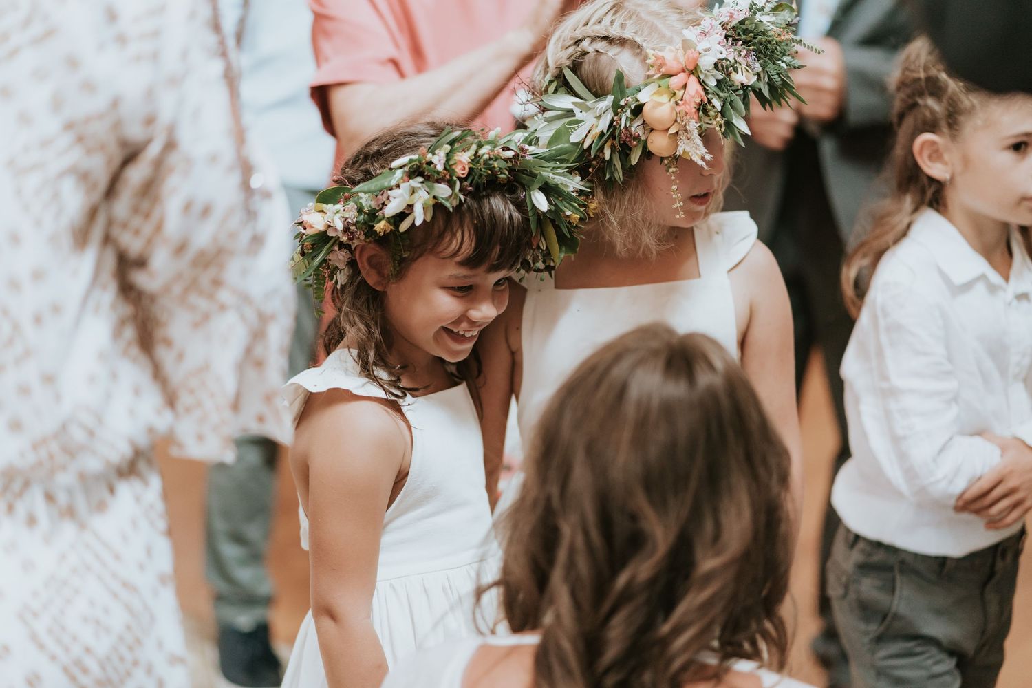 Wedding party gathers outdoors with floral crowns and delicate lace dresses for an intimate celebration.