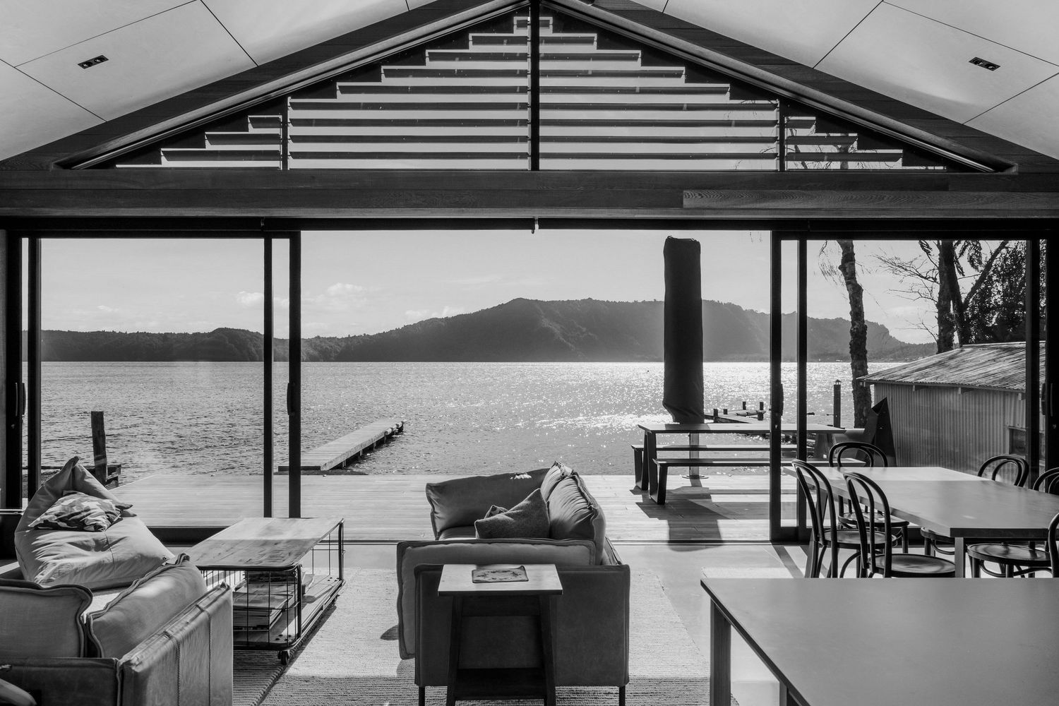 Contemporary waterfront home with expansive glass windows and horizontal lines overlooks a serene lake view.