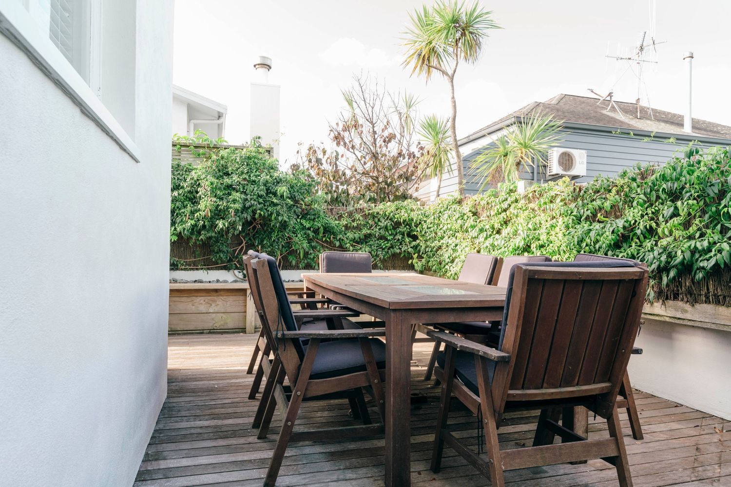Outdoor patio area with wooden furniture and lush greenery.