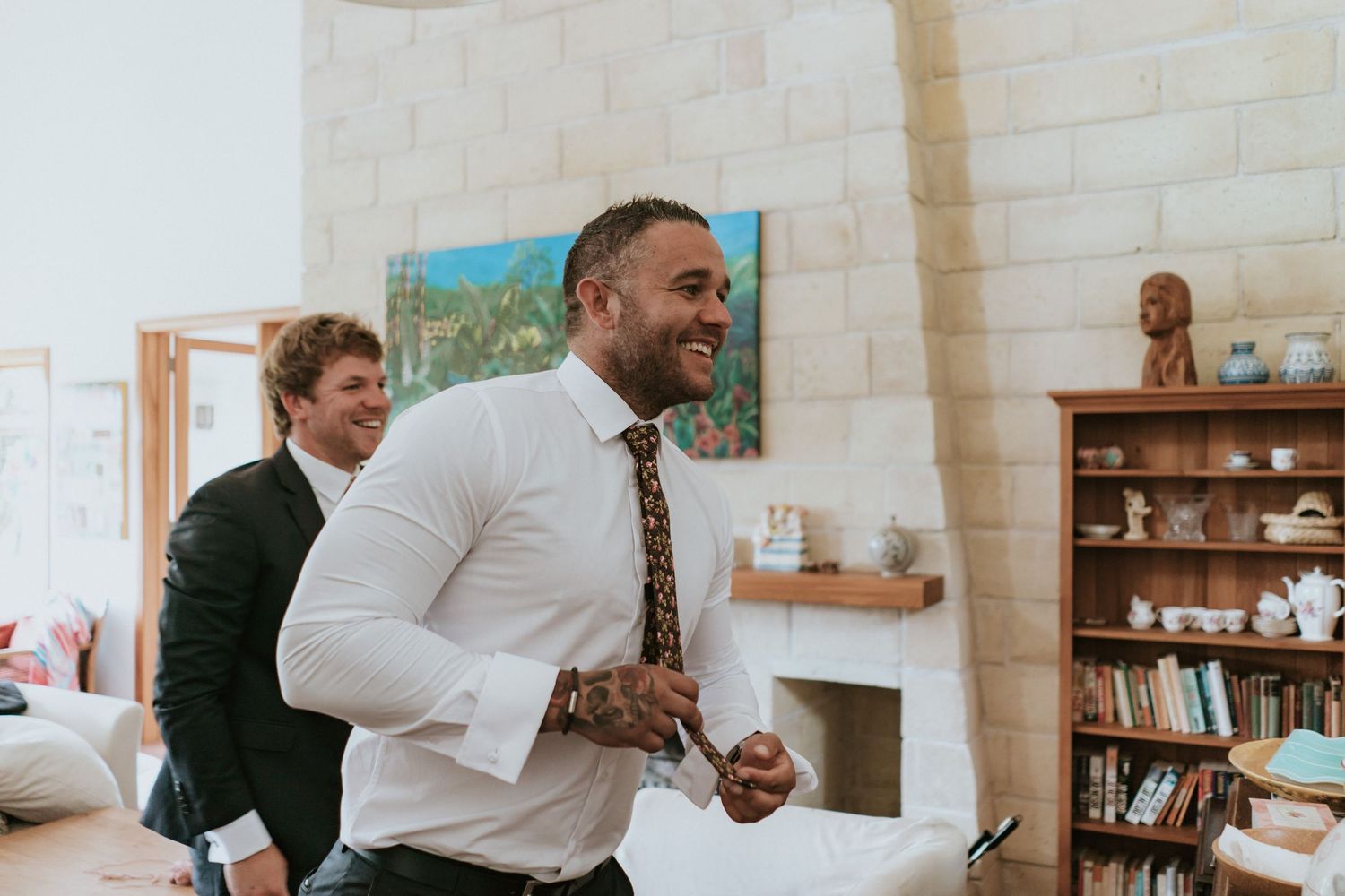 Two people share a joyful moment in a bright living room with white walls and built-in bookshelves.