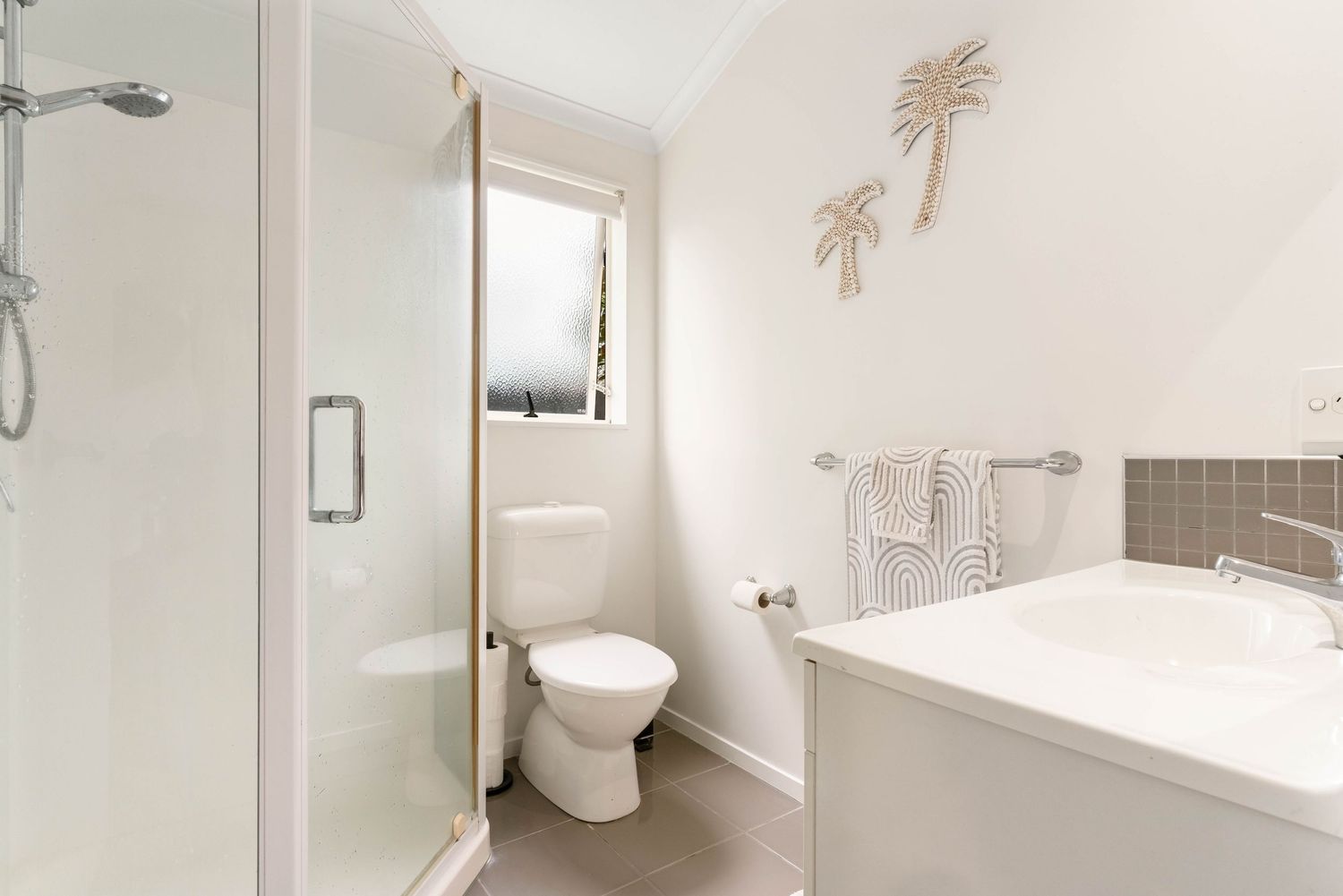 Clean white bathroom with modern fixtures, glass shower enclosure, and minimalist design elements.