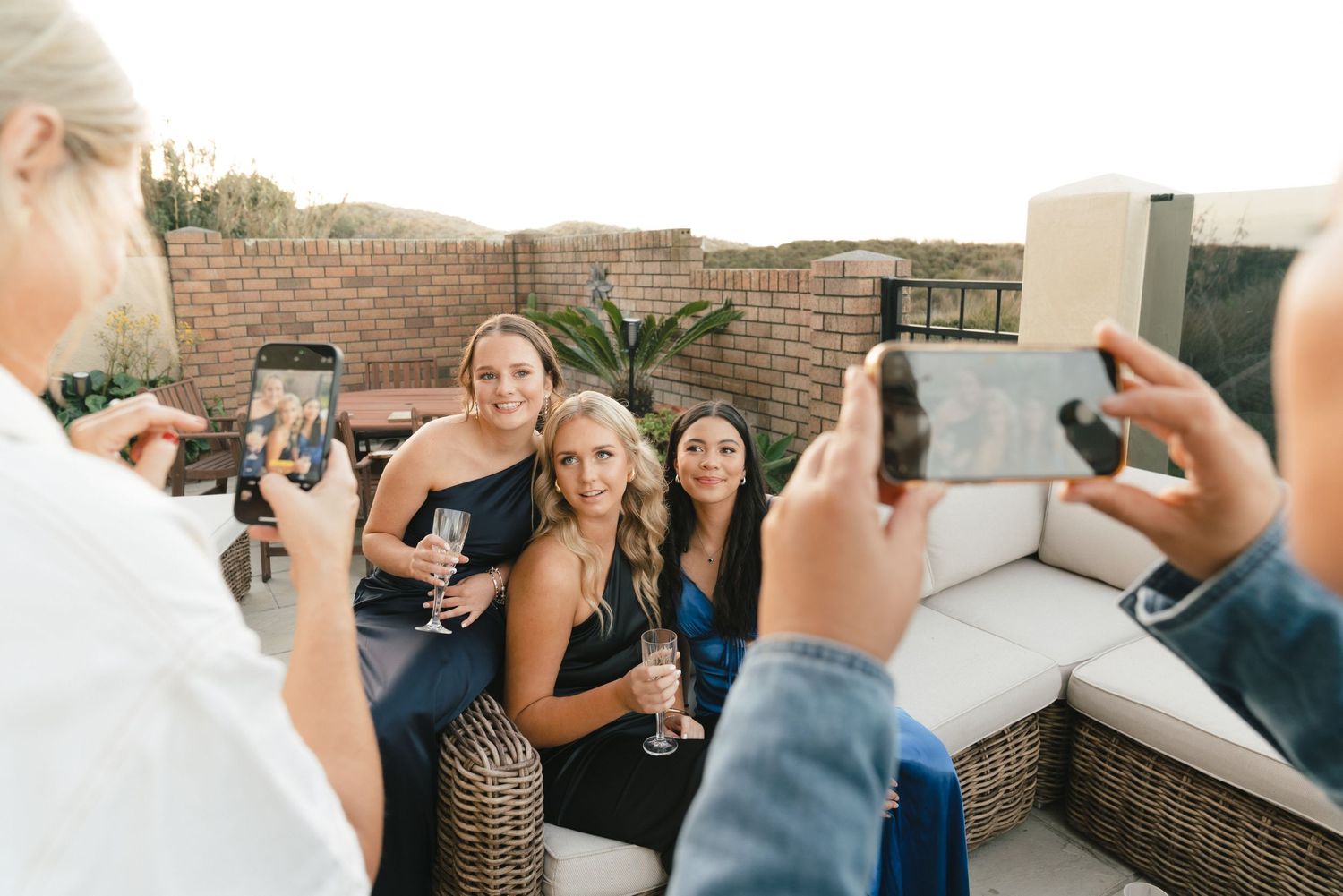 Casual party scene with guests mingling and taking photos on covered outdoor patio.