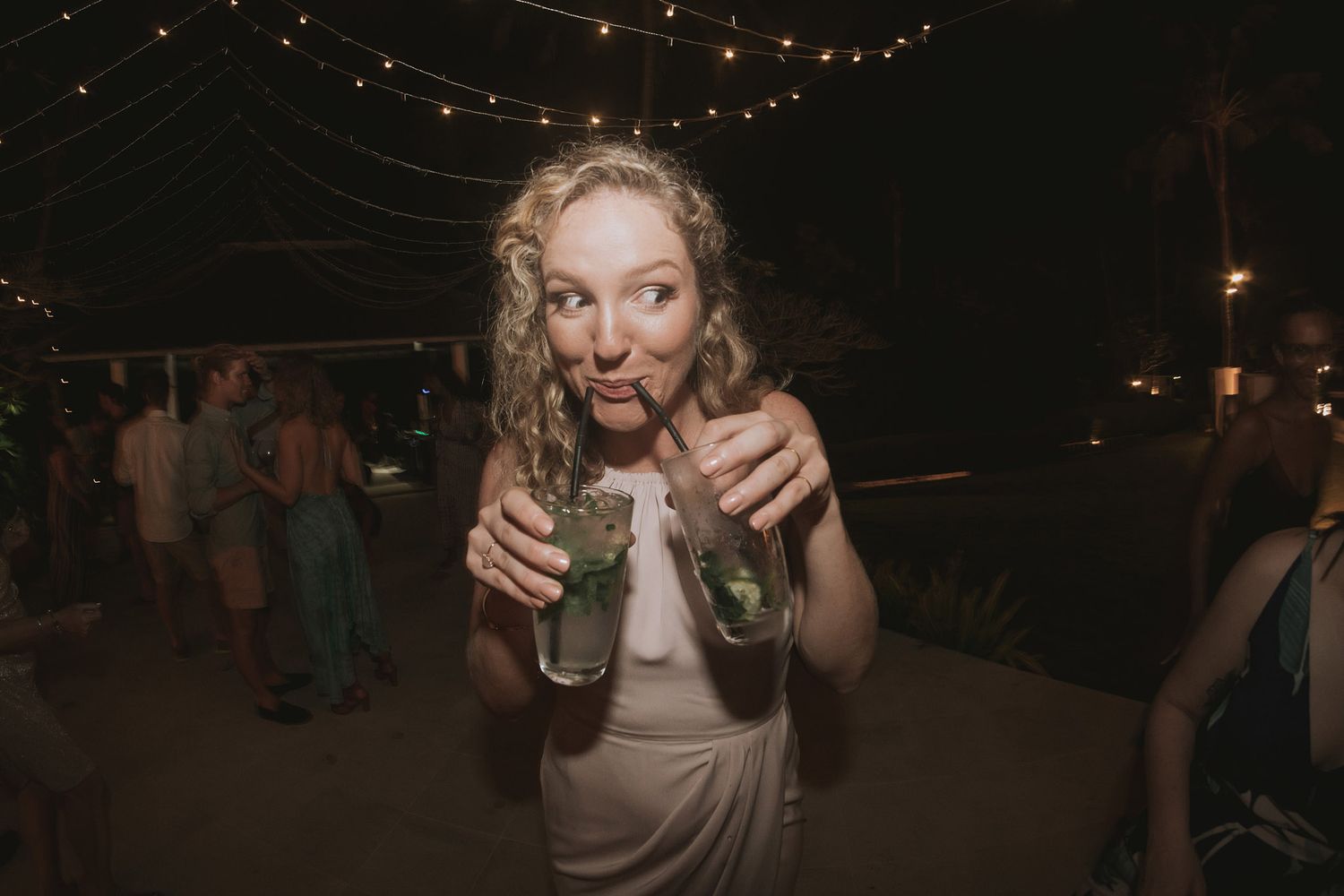 A joyful guest makes an animated expression while dancing at a dimly lit wedding reception.