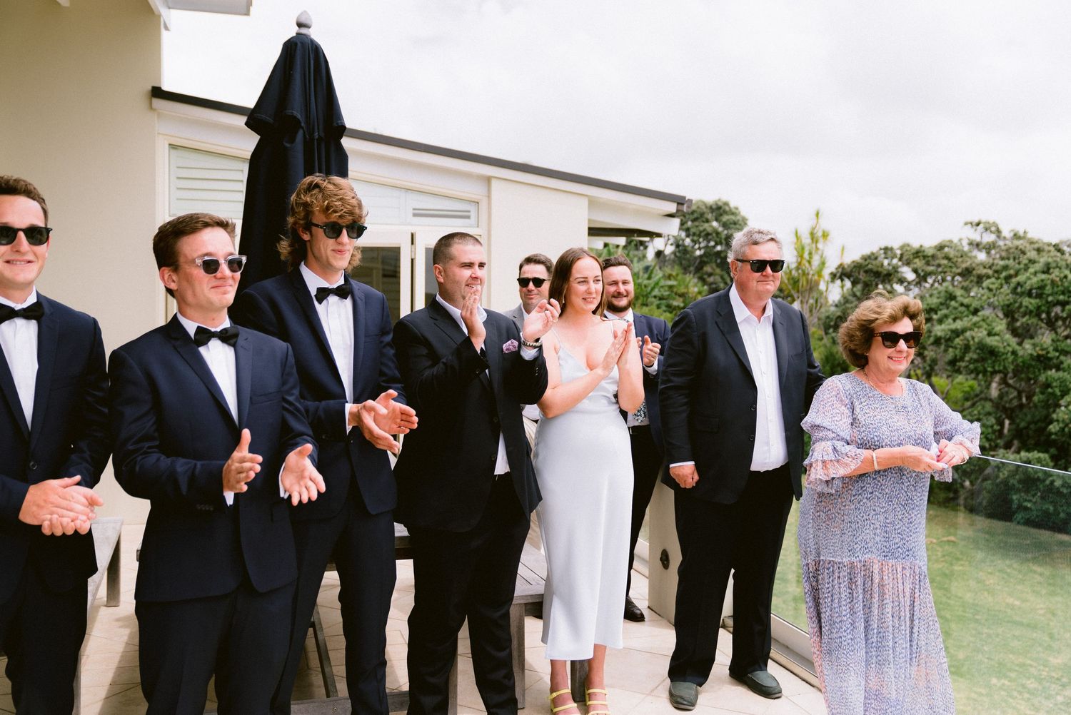 A group in formal attire gathered outdoors at an elegant wedding event.