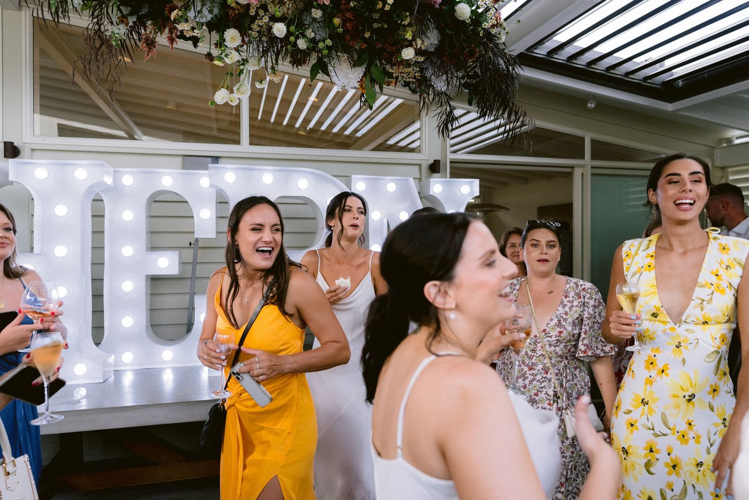 Wedding guests laugh and celebrate during a joyful indoor reception moment.