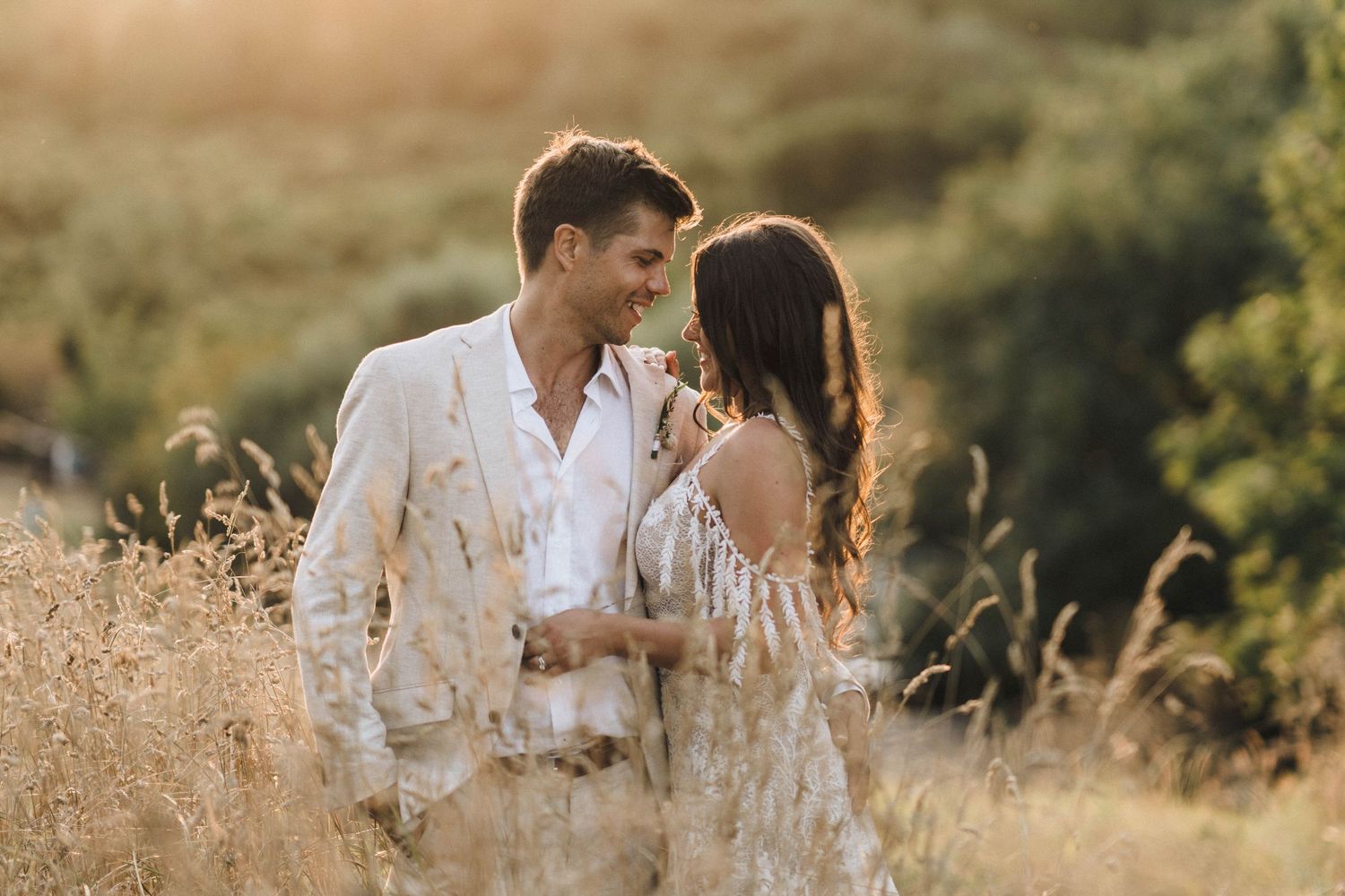 Intimate wedding moment captured in golden field during sunset.