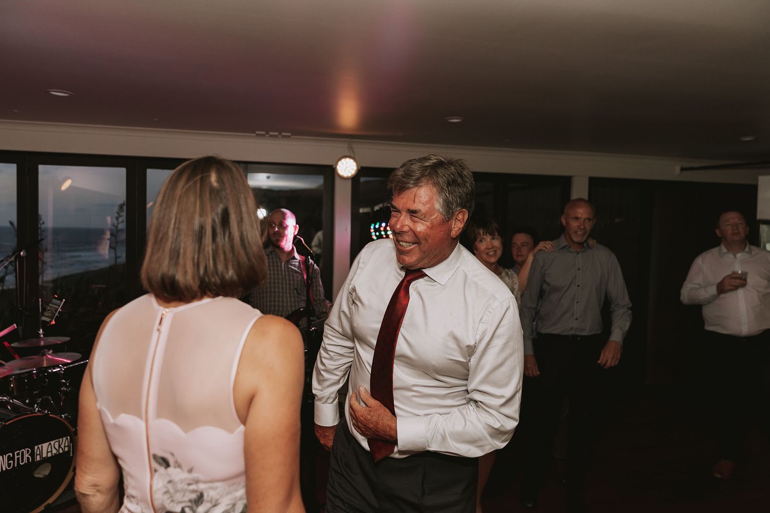 A dimly lit dance floor at a wedding reception with elegant decorations and guests mingling in the background.
