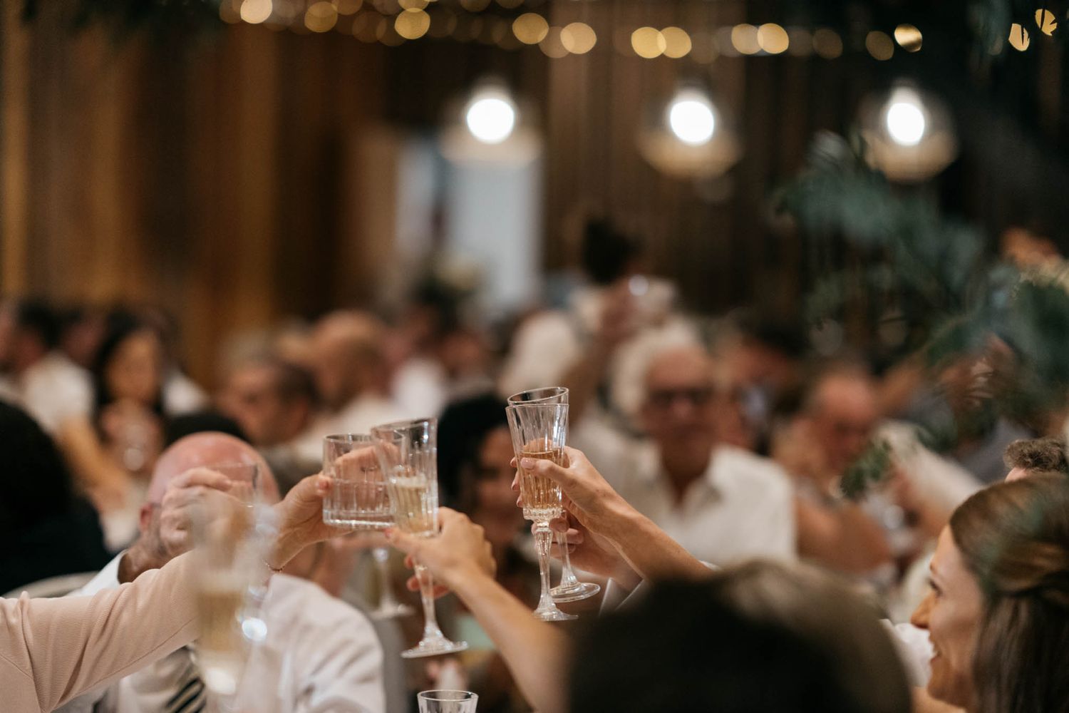 A dimly lit reception venue with soft glowing lights and elegant table settings at a celebration event.