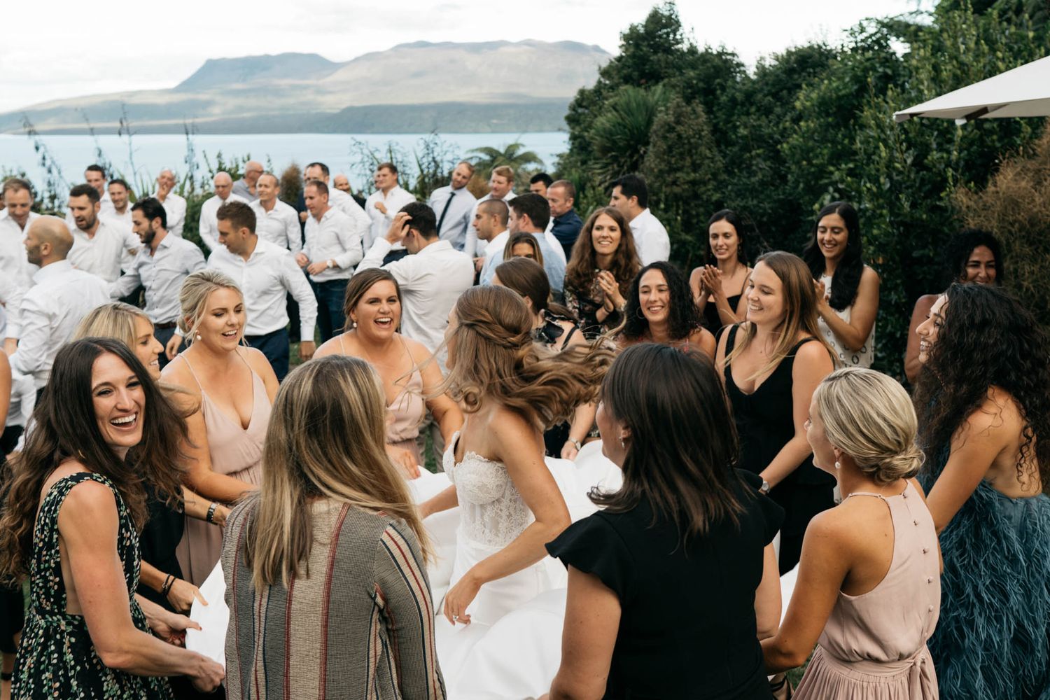Wedding guests mingle and socialize during an outdoor reception gathering by a waterfront venue.