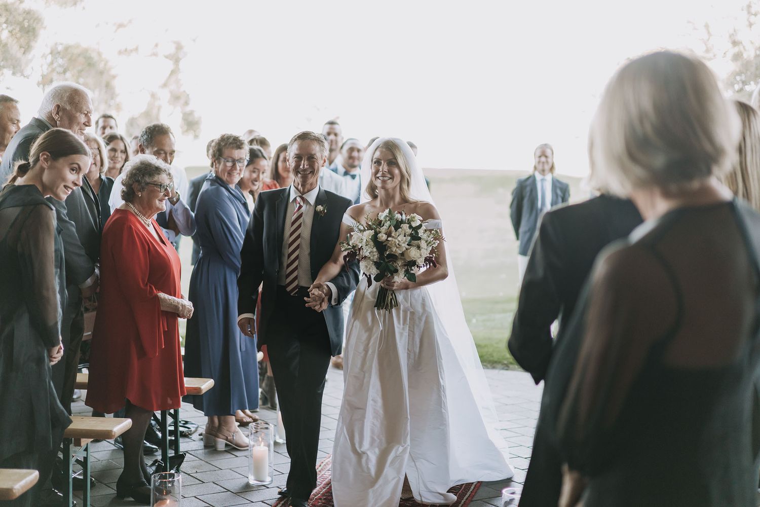 Wedding guests mingle and socialize at an elegant indoor reception venue with natural lighting.