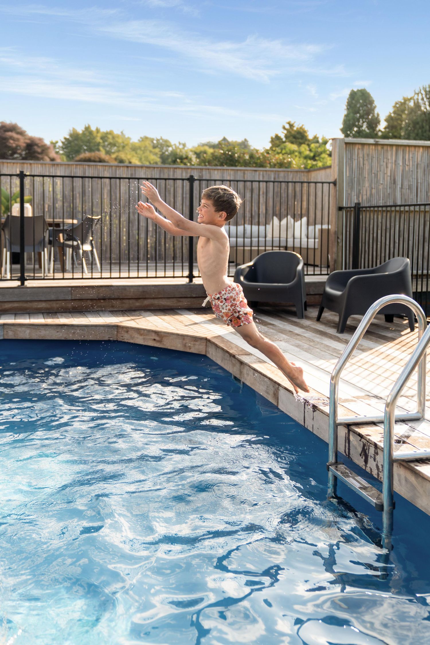 A sequence showing someone diving into a refreshing blue pool from the metal ladder on a sunny day.