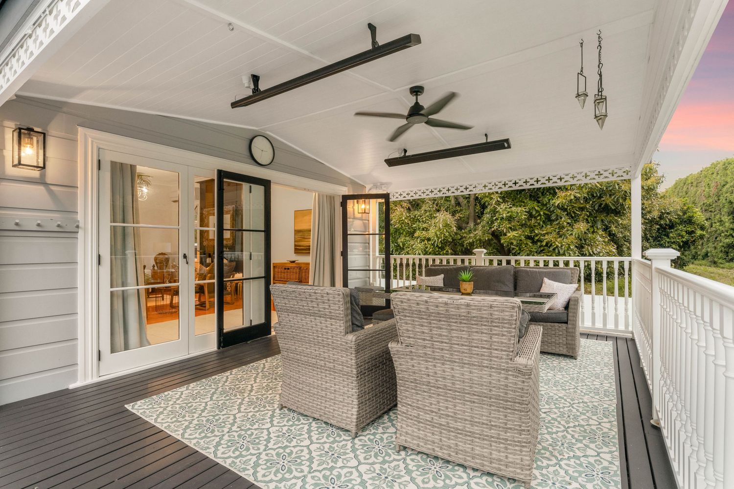 Covered outdoor patio with wicker furniture and decorative tile flooring overlooking lush landscape.