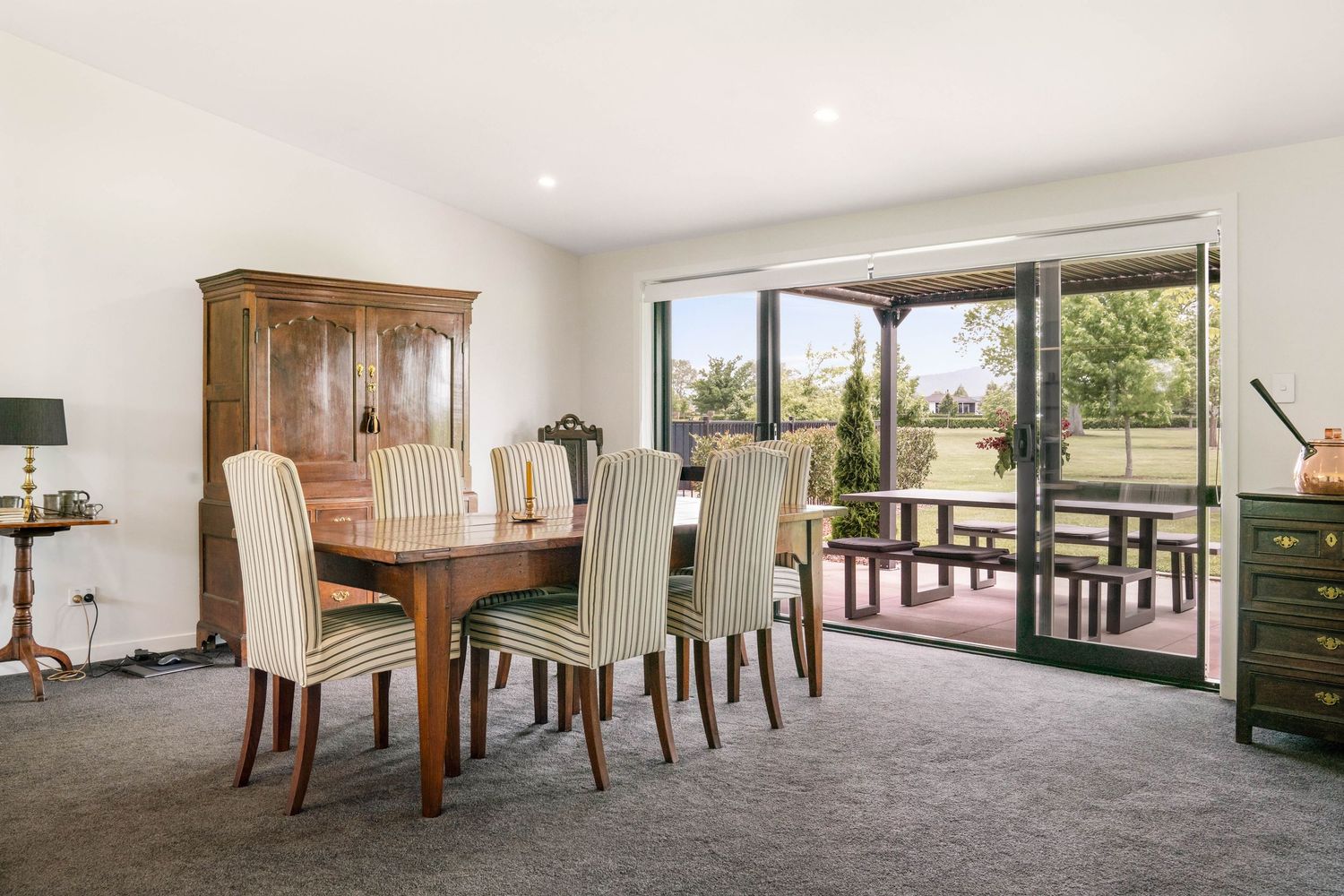 Modern dining room set with upholstered chairs and wooden table in bright interior with large windows and natural light.