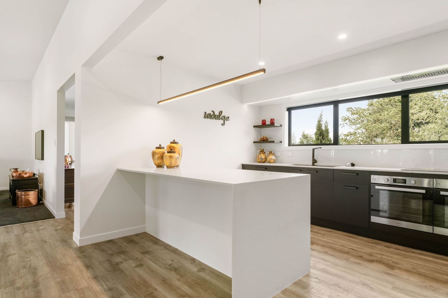 Open concept interior living space with white walls, wood floors and large windows providing natural light.