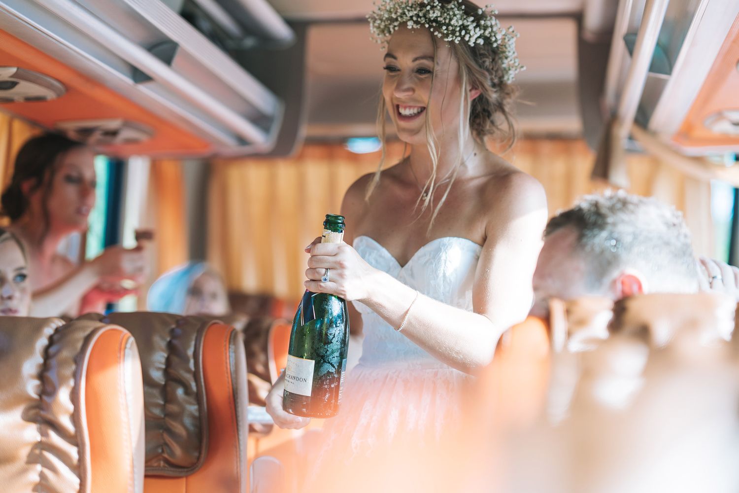Person in wedding attire enjoying a beverage in a rustic vehicle interior.