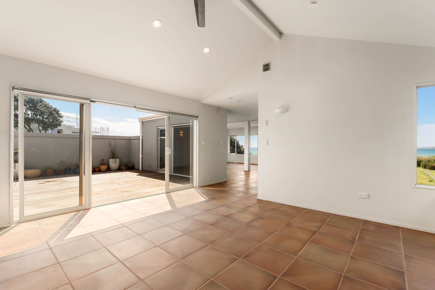 Modern living space with glass doors opening to outdoor patio and terracotta floors.