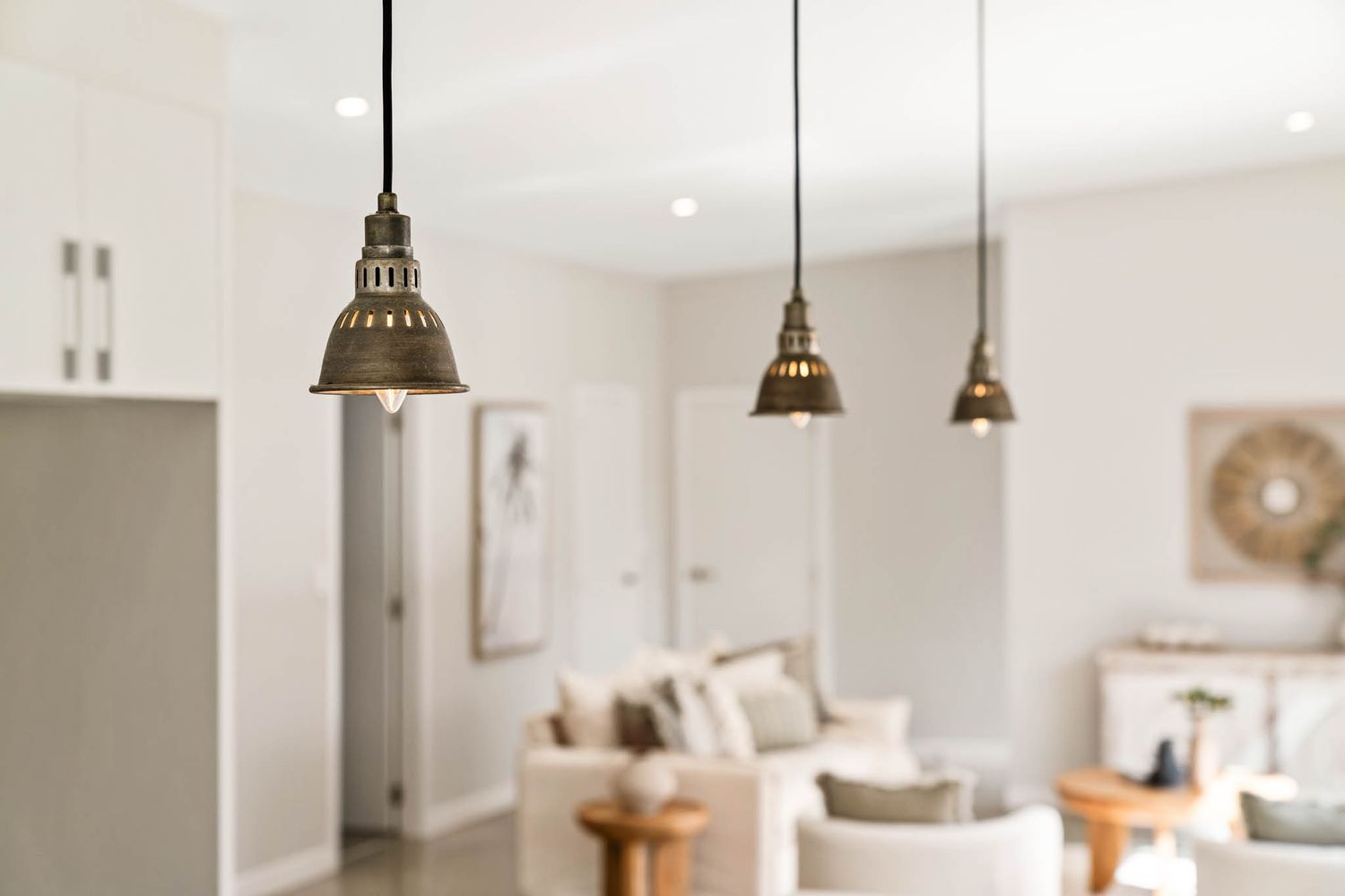 Vintage brass pendant lights hang over a bright interior space with neutral decor.