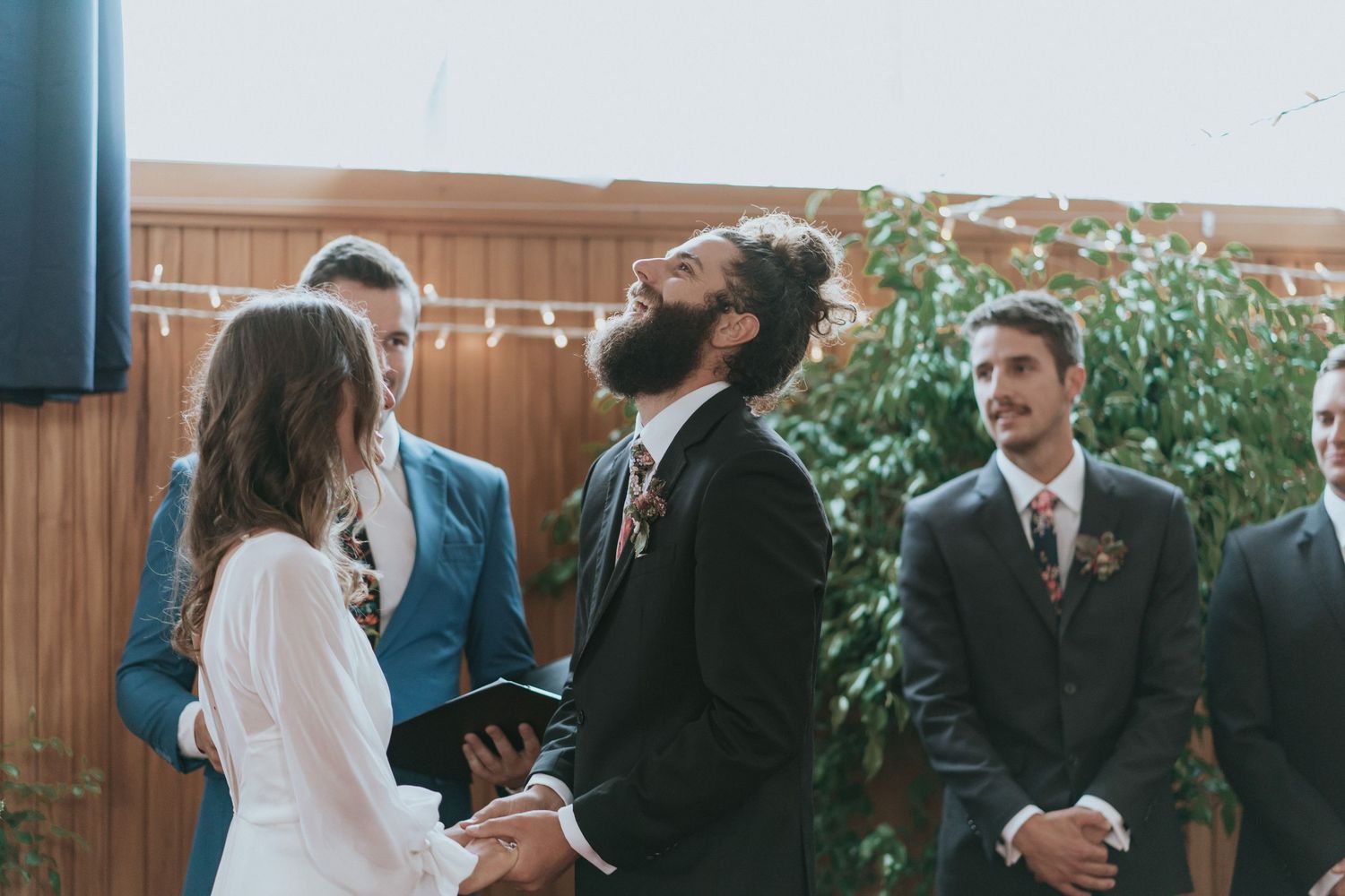 Couple exchanges vows during an intimate outdoor wedding ceremony with wooden fence and greenery backdrop.
