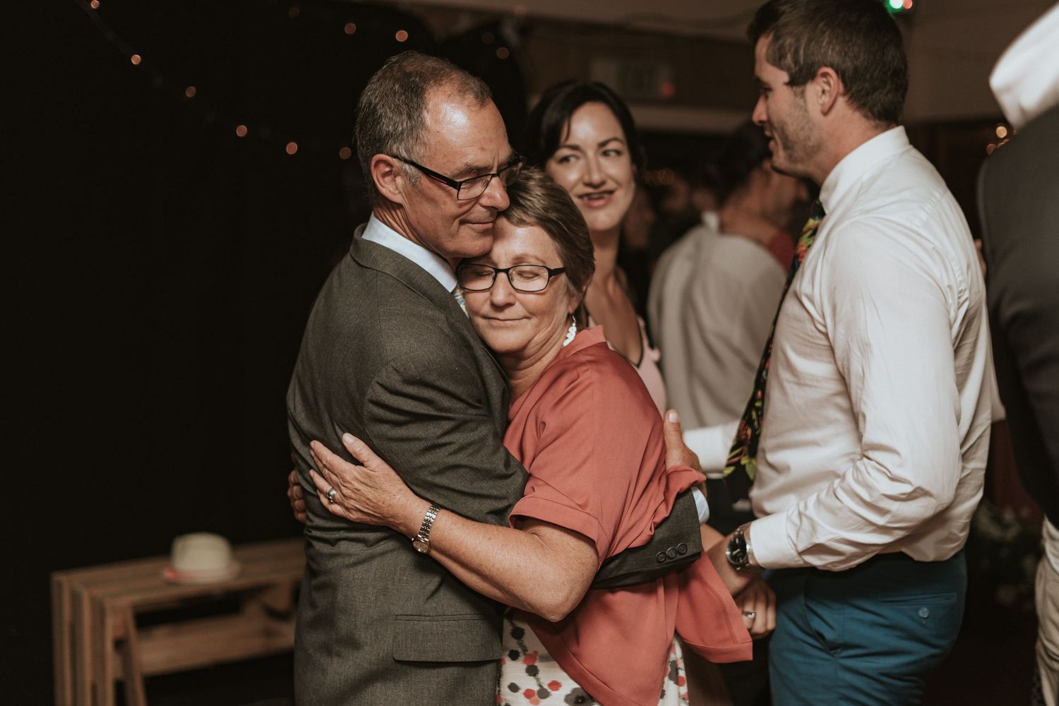 Several couples slow dance together in an intimate indoor venue with soft lighting.