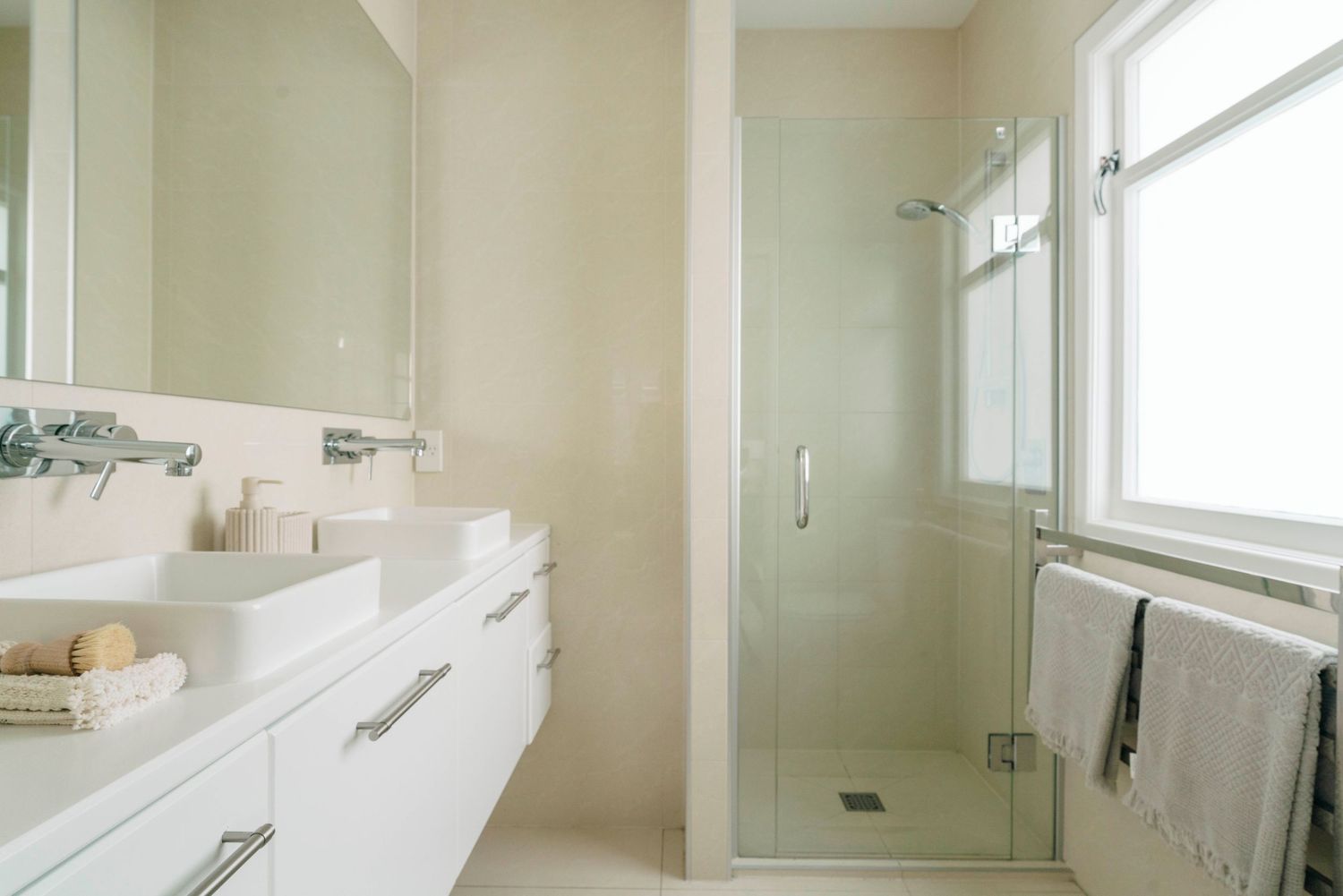 Clean, minimalist bathroom with white fixtures and natural light streaming through windows.