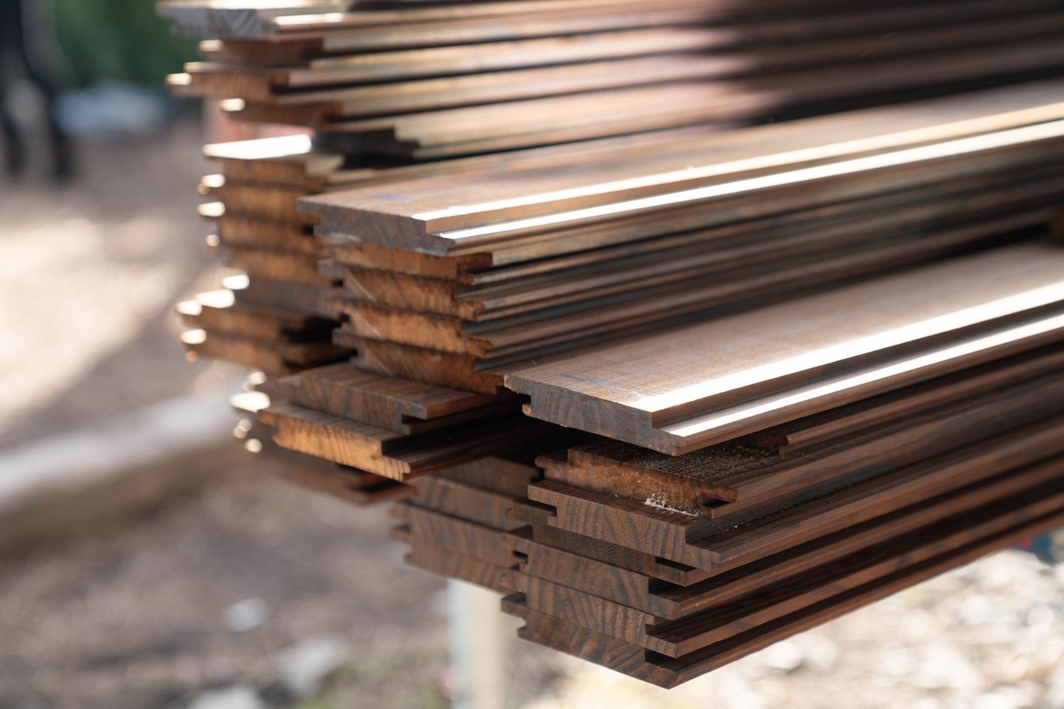 A close-up stack of brown wooden planks with staggered edges in natural lighting.