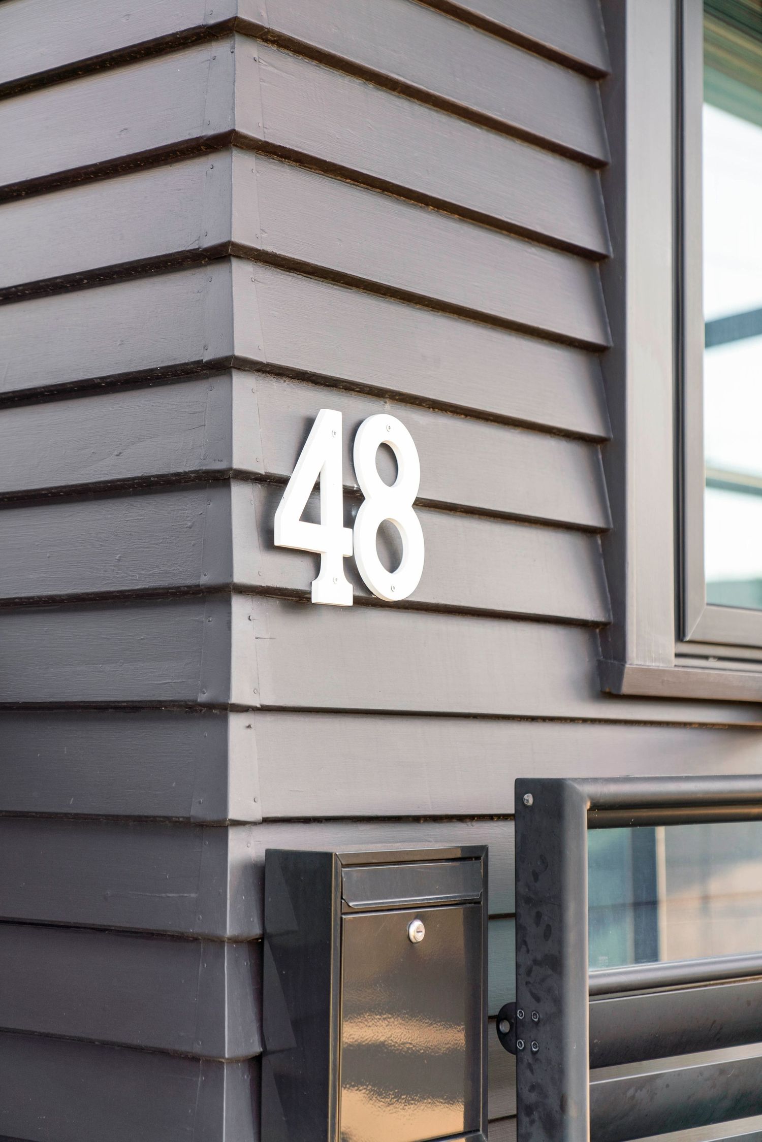 Modern house numbers displayed in white against dark siding showing numbers 40 in sequence.