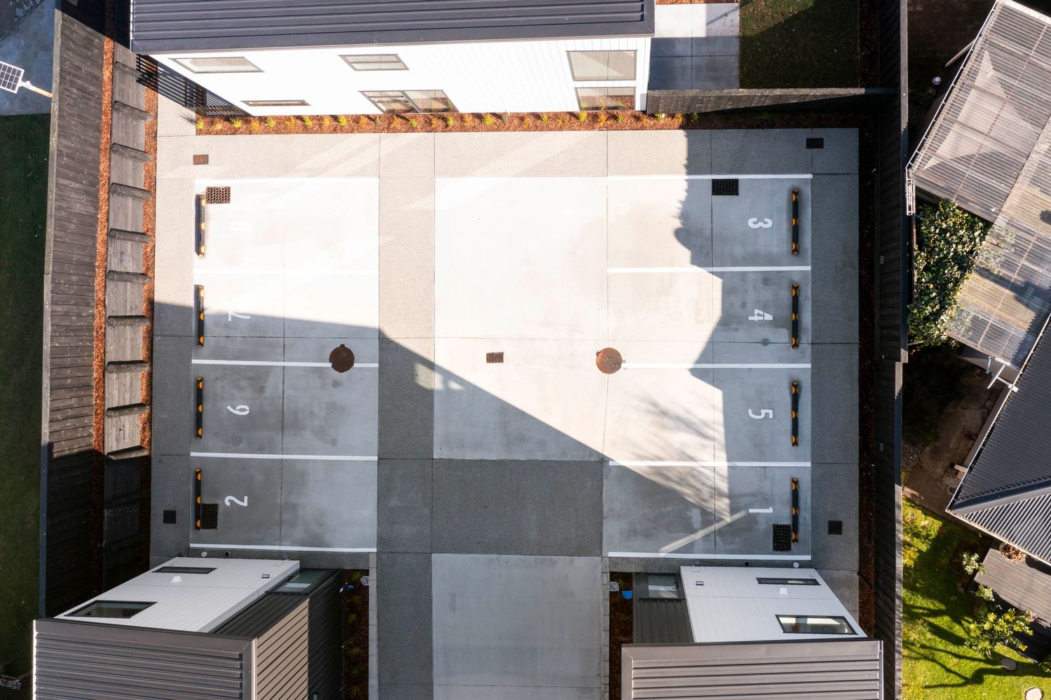 Overhead view of a modern patio with geometric shadows cast across the concrete surface.