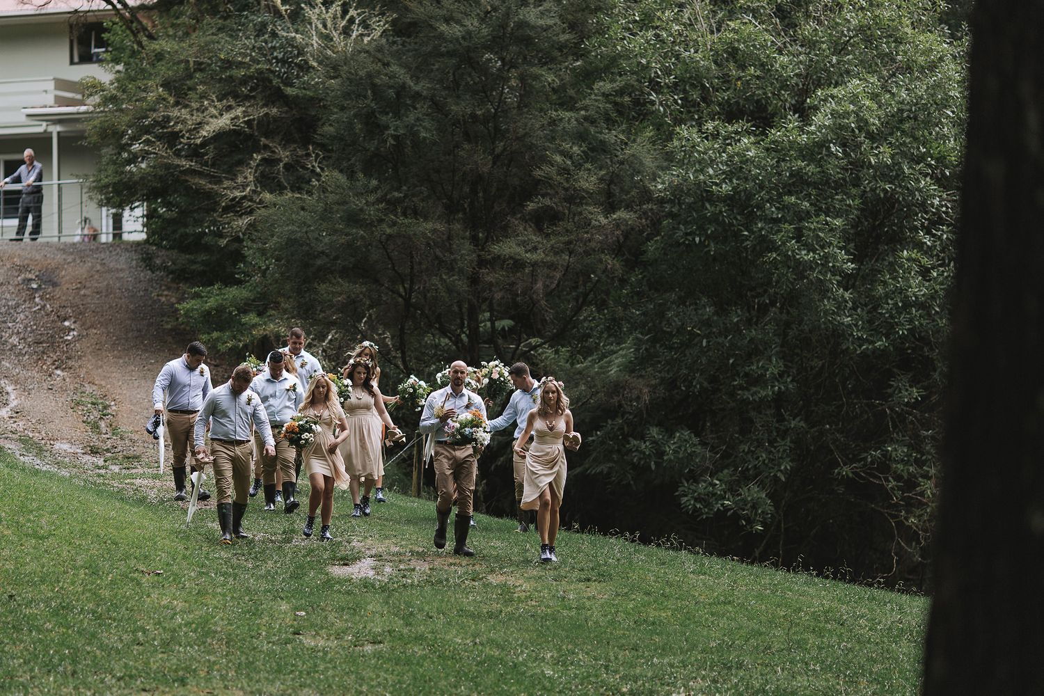 A joyful group runs down a grassy hill in casual attire during an outdoor celebration.