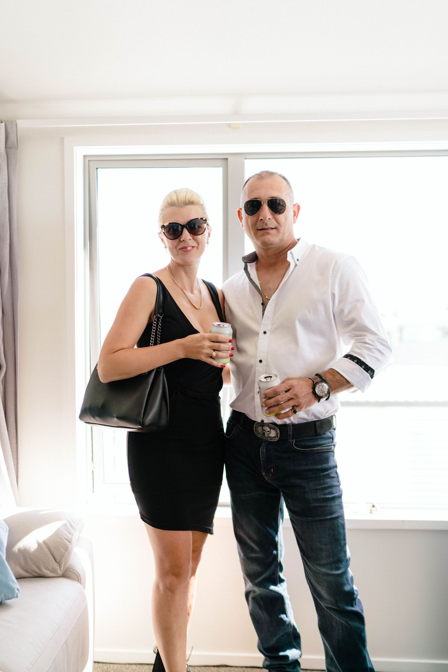 Two people in contrasting black and white outfits posing in a bright interior space.