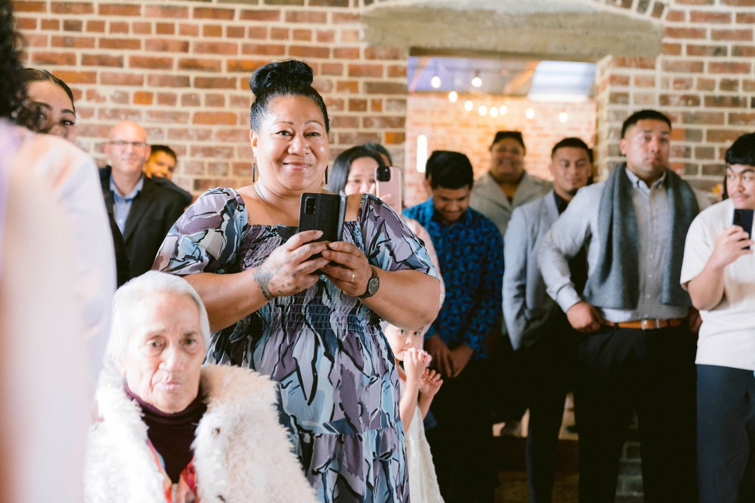Wedding guests enjoying a reception celebration in an industrial brick venue with elegant lighting.